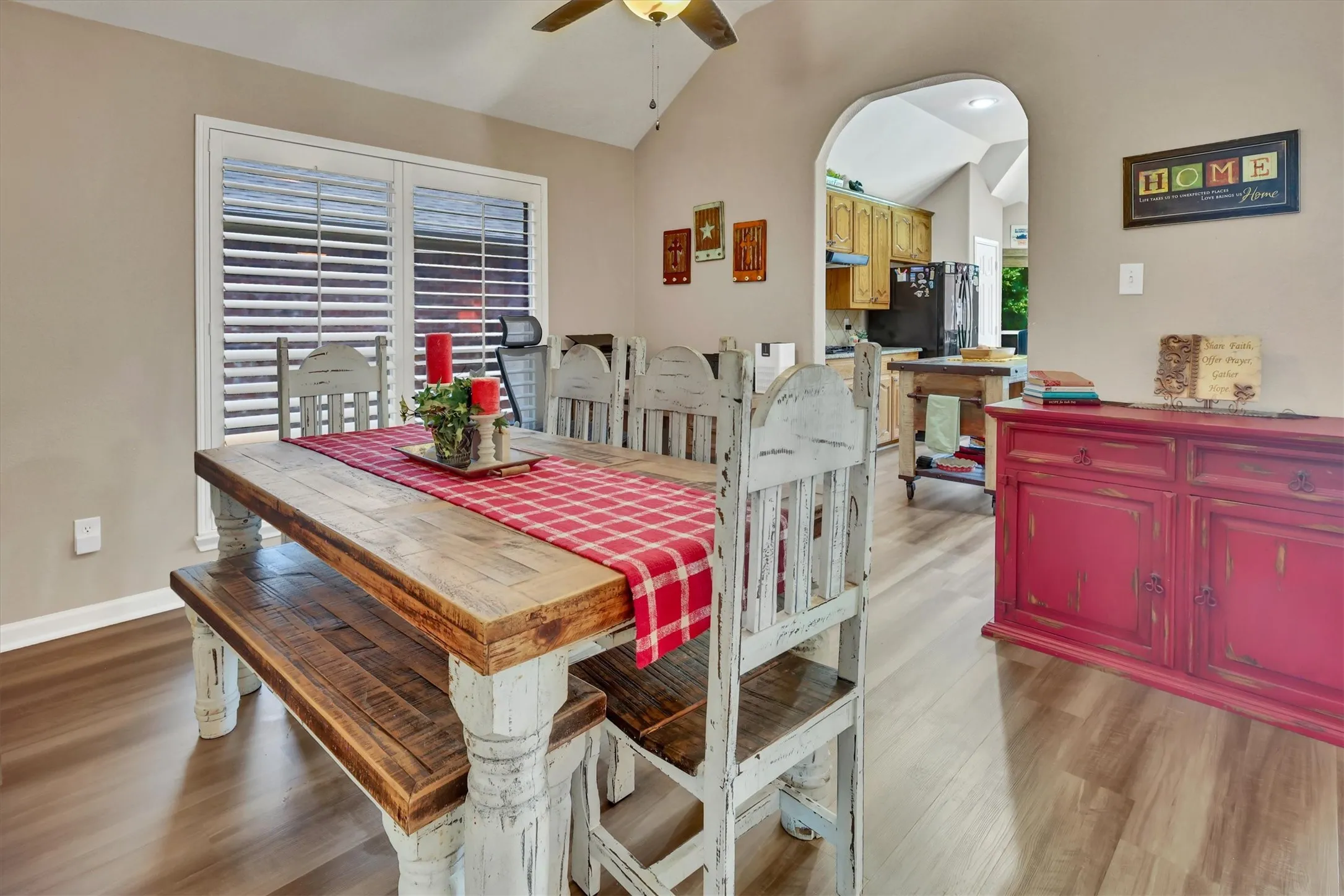 Bright dining area showcasing a rustic wood farmhouse table with white turned-leg chairs, complemented by a coordinating bench
