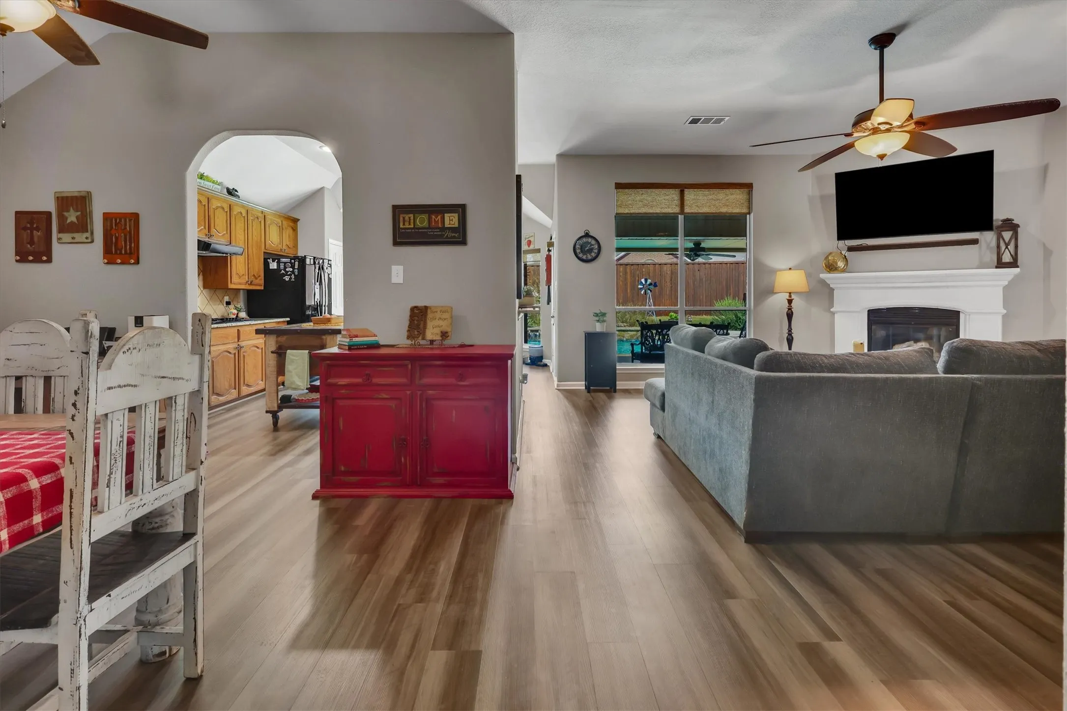 Vaulted ceilings with ceiling fans, wood-finish flooring, a white mantel fireplace, and arched doorways