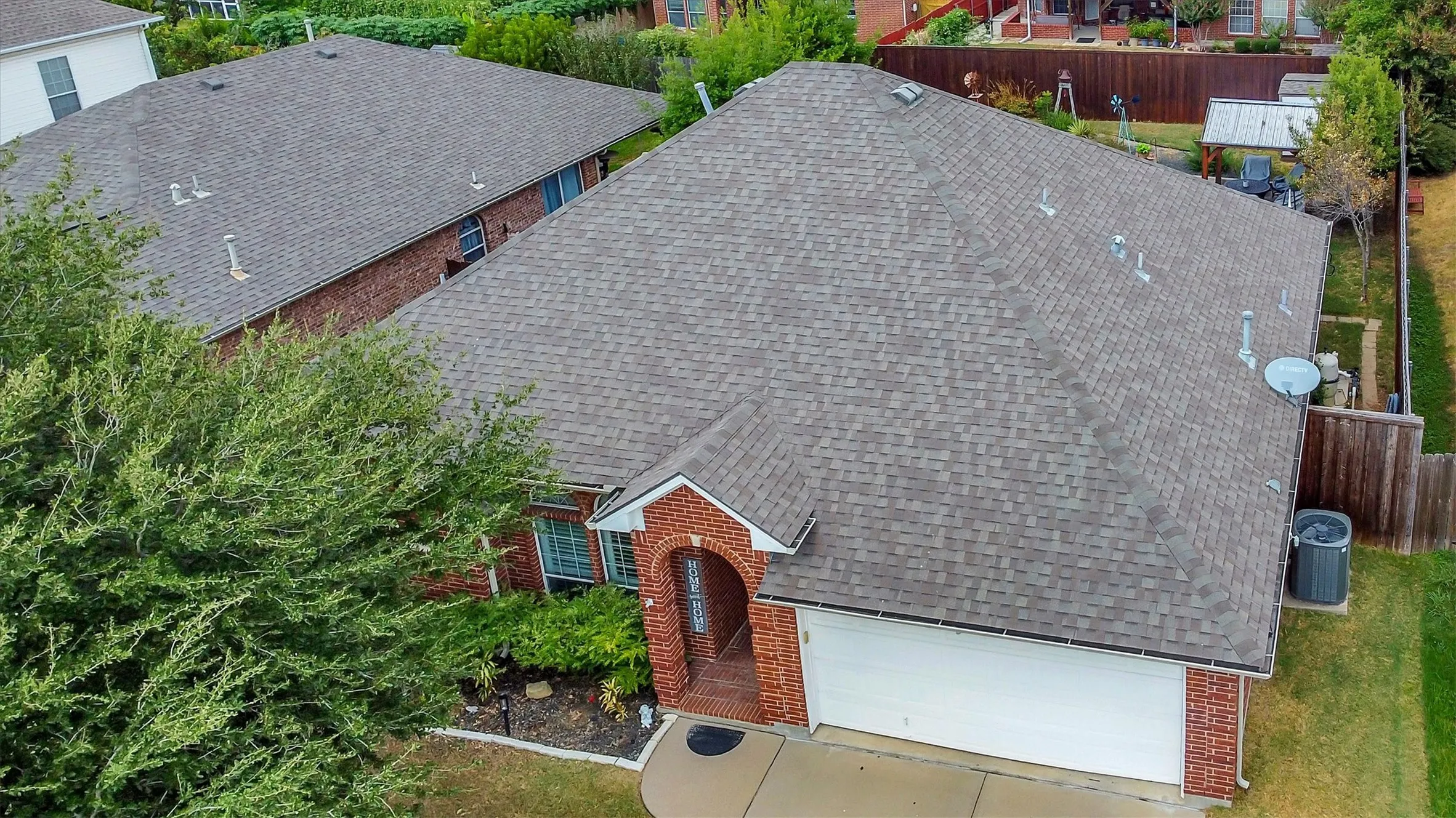 Brick exterior featuring an arched entry, two-car garage, and shingle roofing