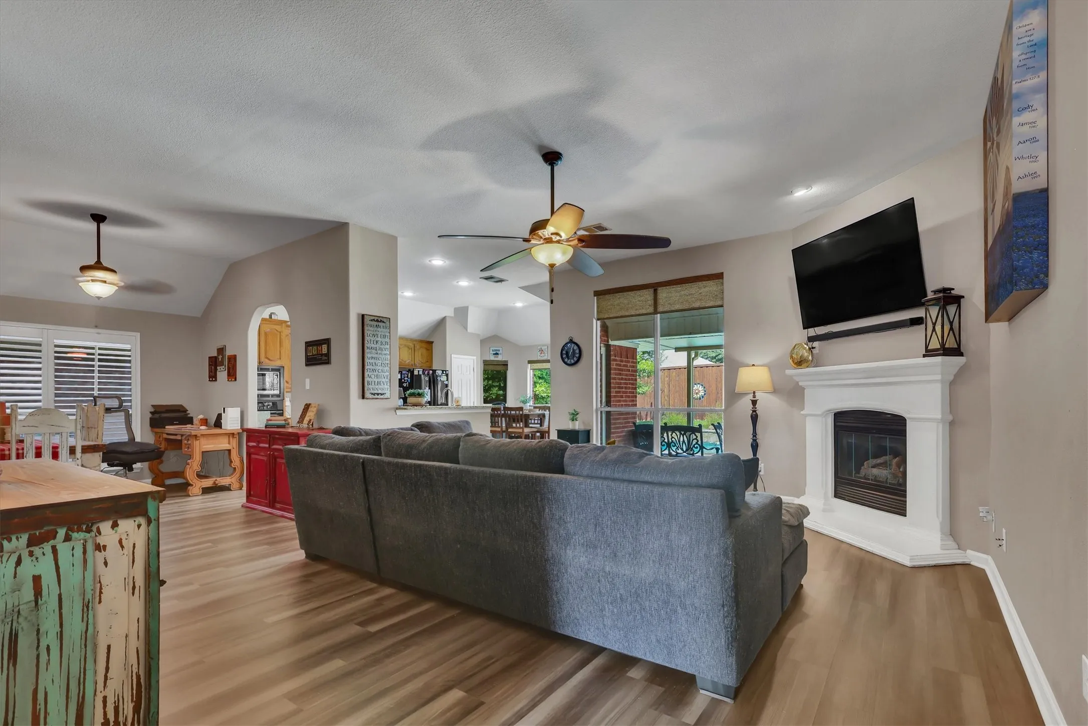 Spacious interior with vaulted ceilings, wood-finish flooring, a built-in corner fireplace, and recessed lighting