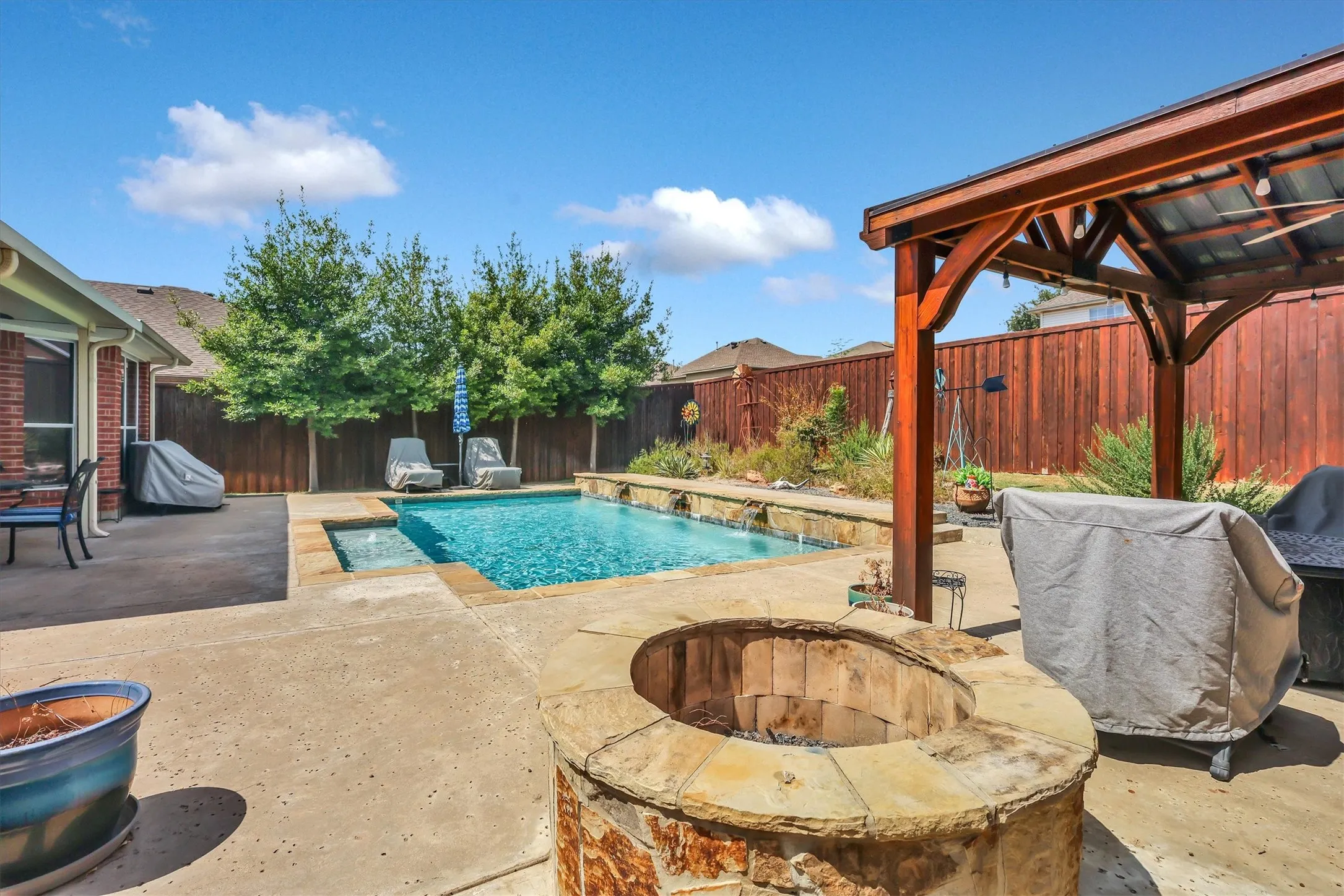 Backyard oasis featuring a swimming pool with integrated spa, stone coping, and water features