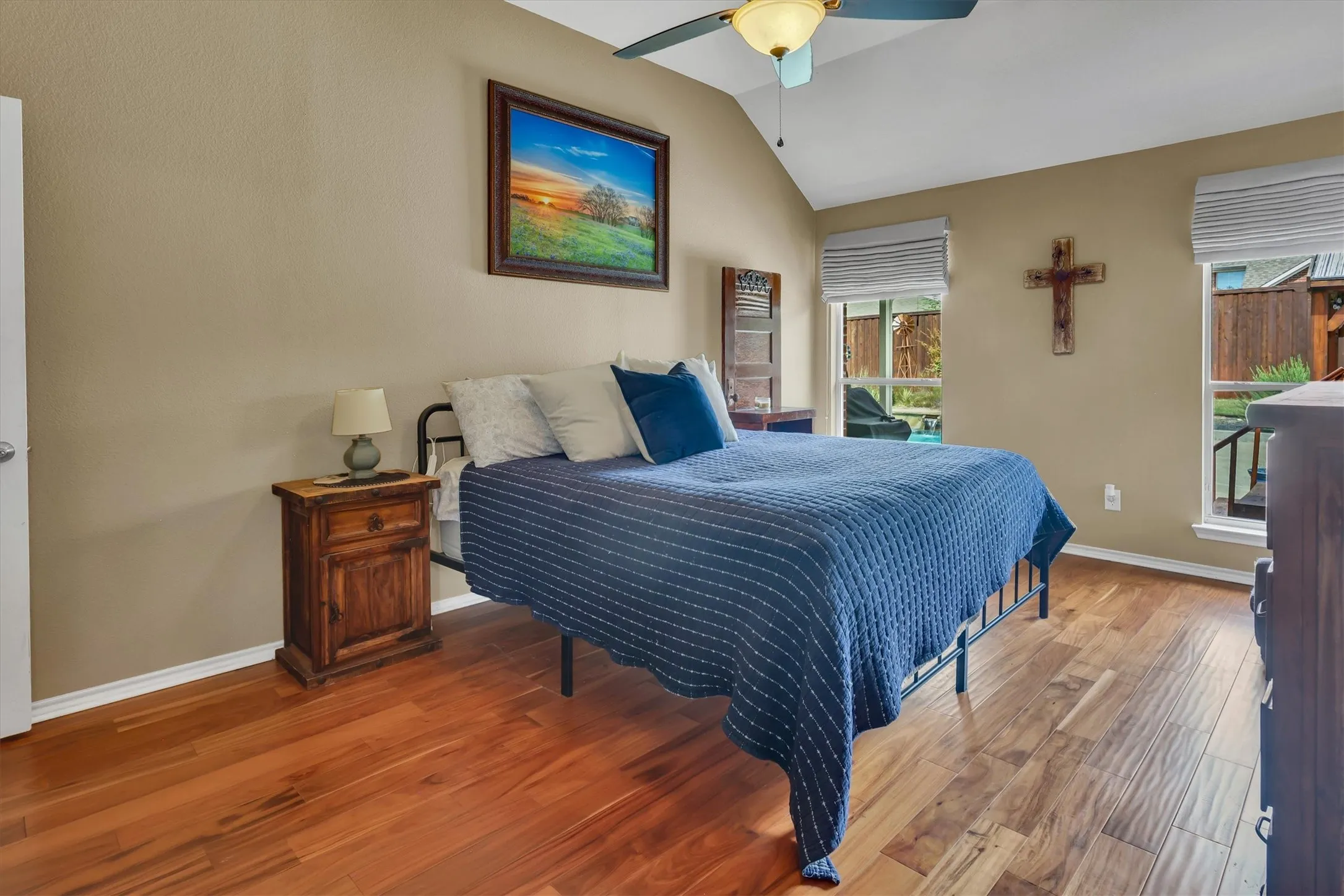 Vaulted ceiling with a ceiling fan, wood-finish flooring, and multiple windows with blinds