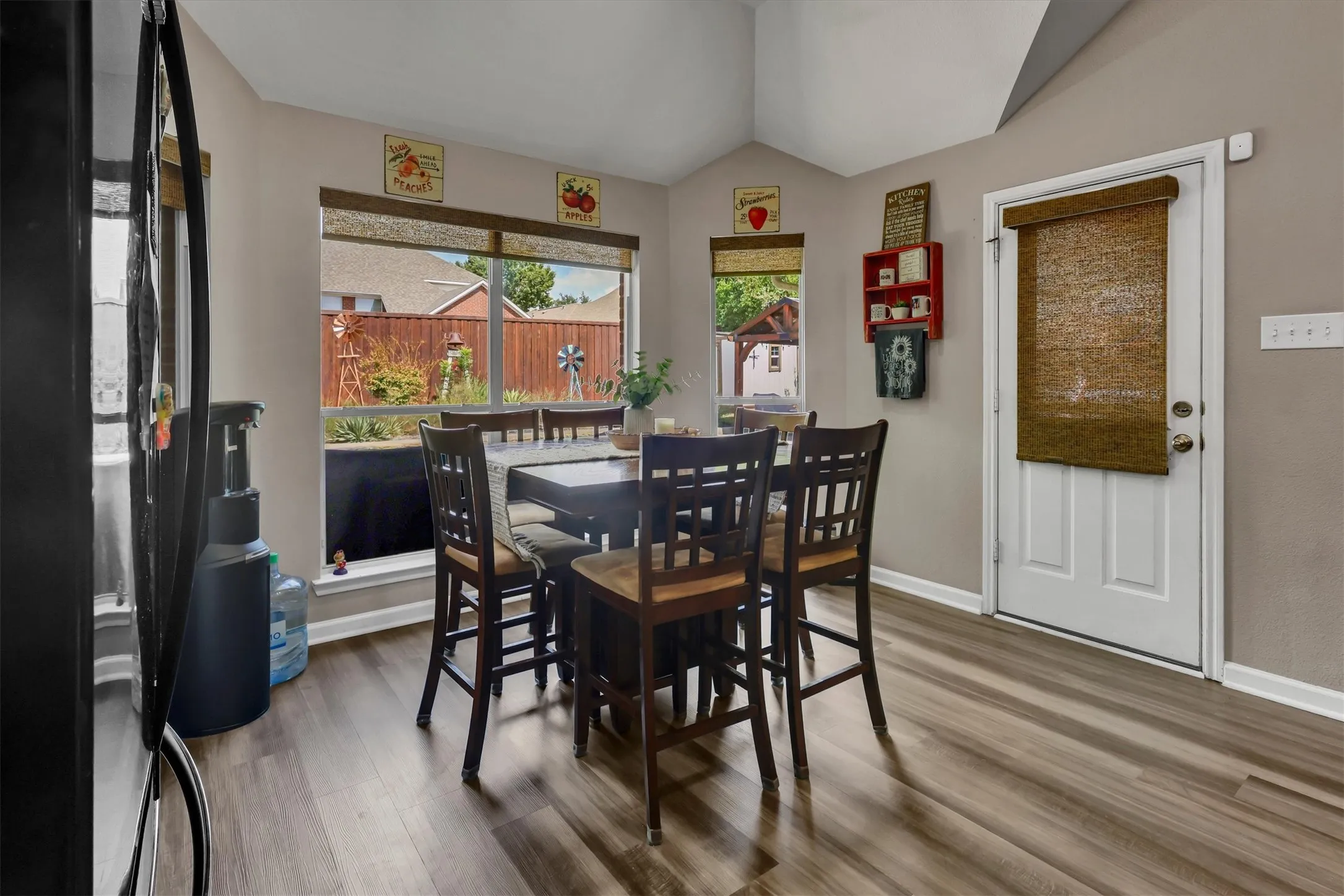 Vaulted ceiling, wood-finish flooring, multiple windows, and exterior access door