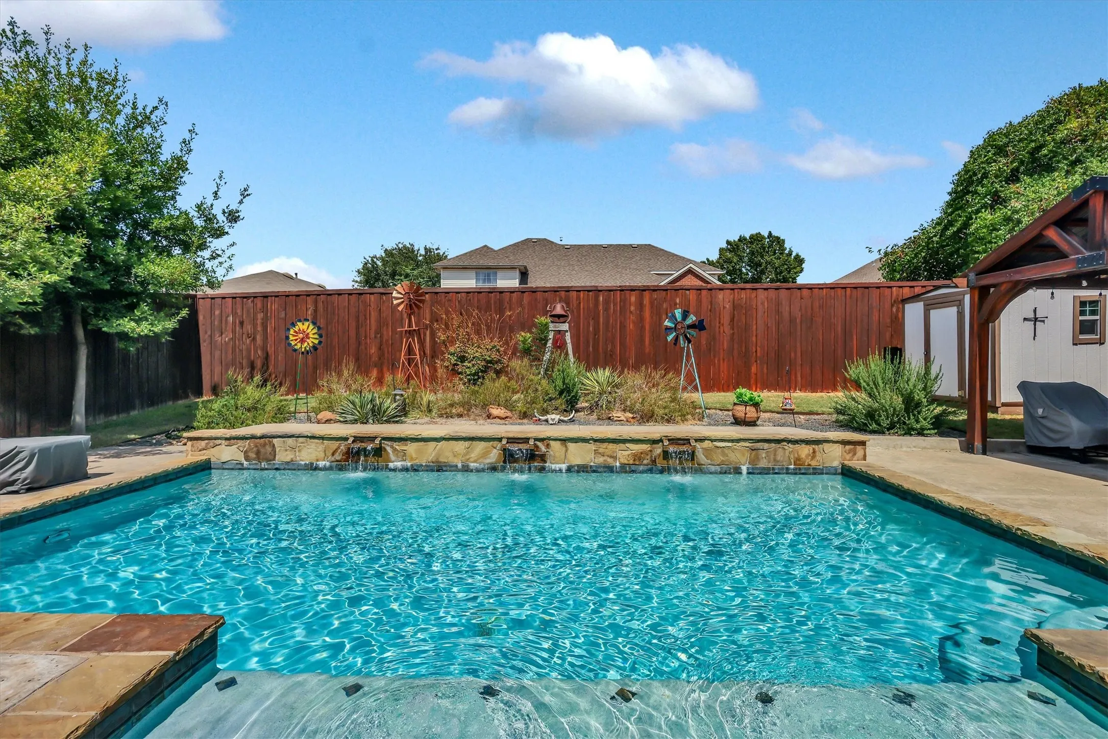In-ground swimming pool with stone coping, water features, and an integrated spa