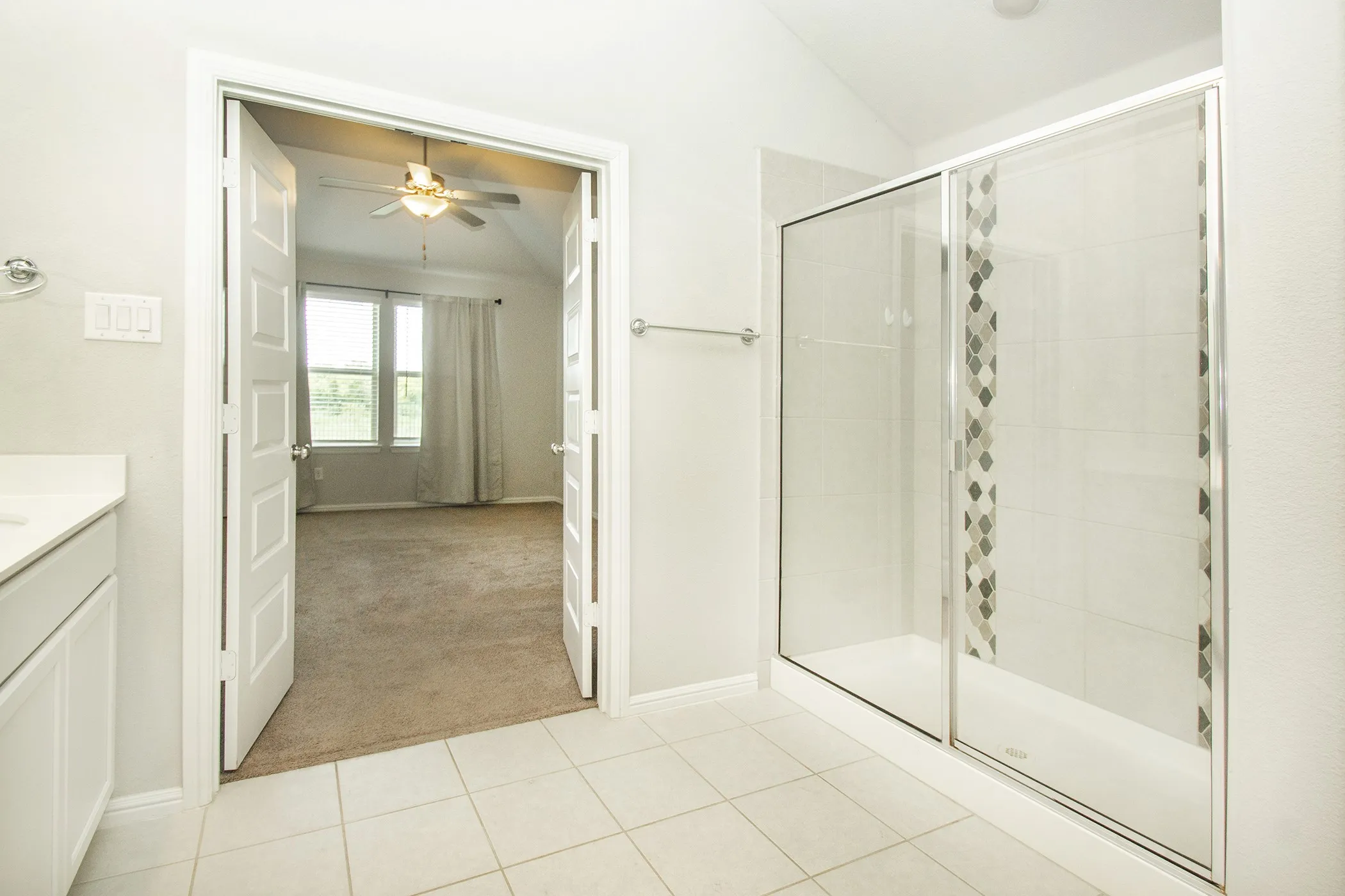 Bathroom with vaulted ceiling, a stall shower, vanity, tile patterned floors, and a ceiling fan