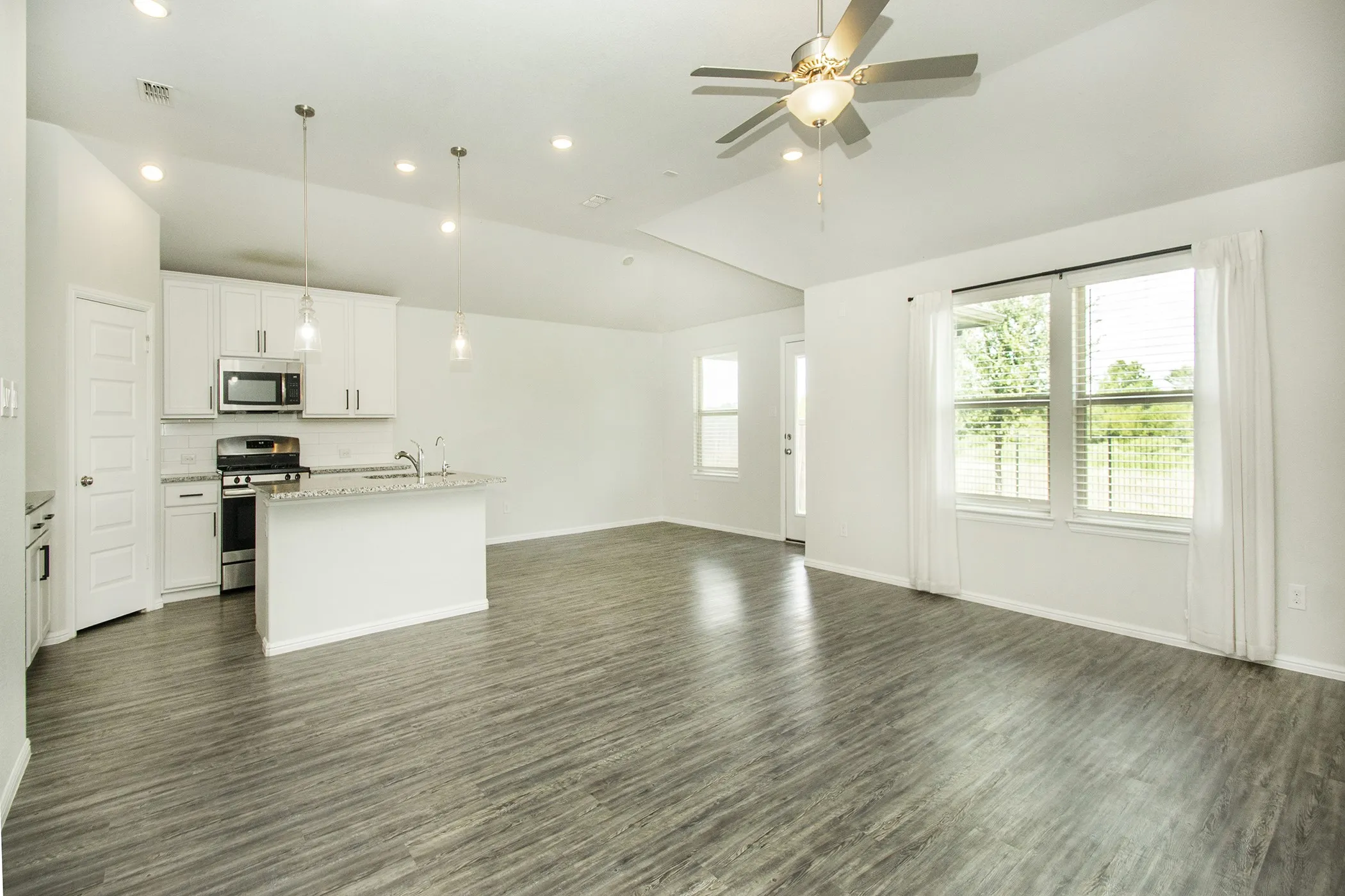 Unfurnished living room featuring dark wood finished floors, lofted ceiling, ceiling fan, and recessed lighting