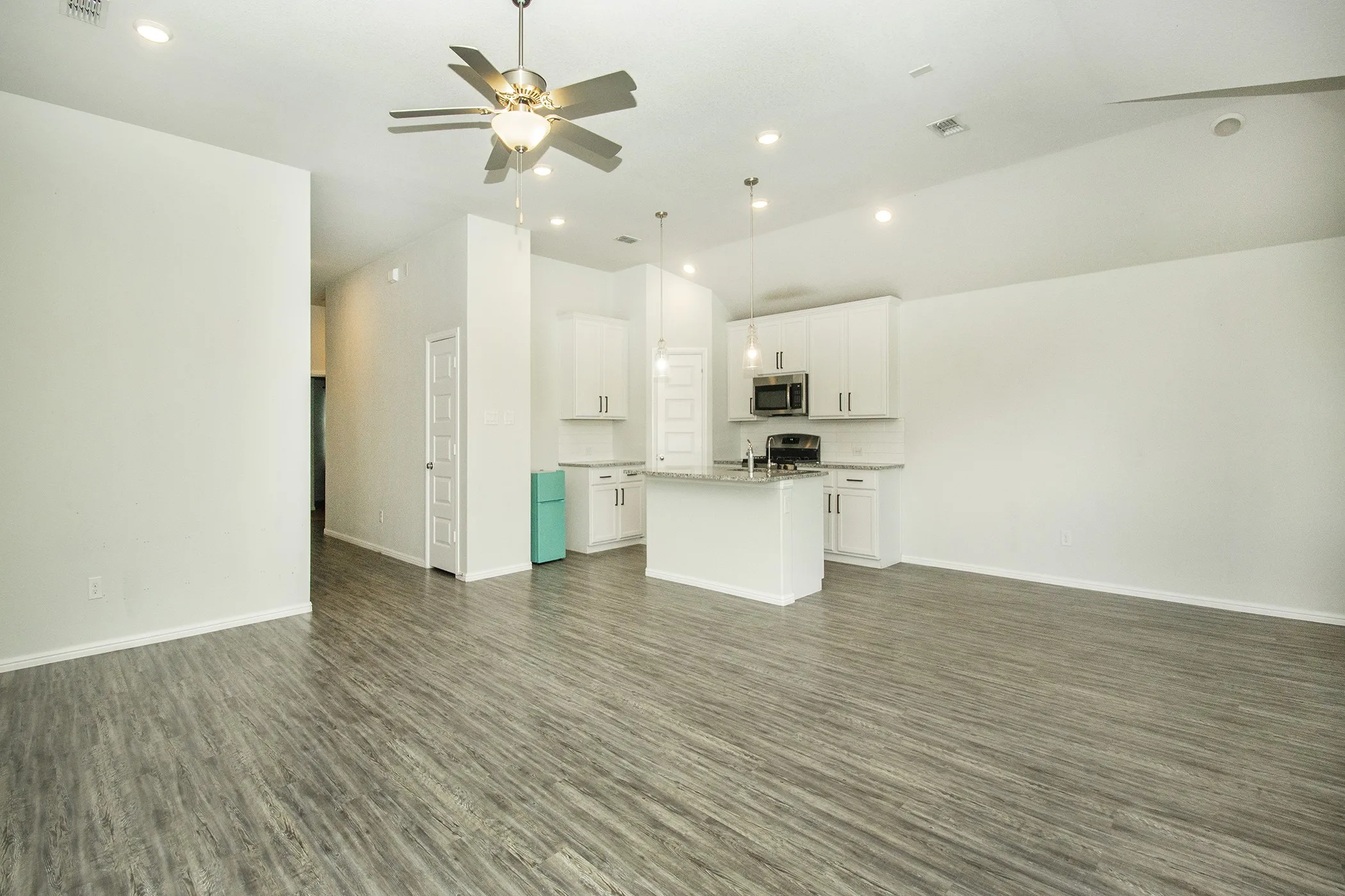 Unfurnished living room featuring wood finished floors, a ceiling fan, and recessed lighting