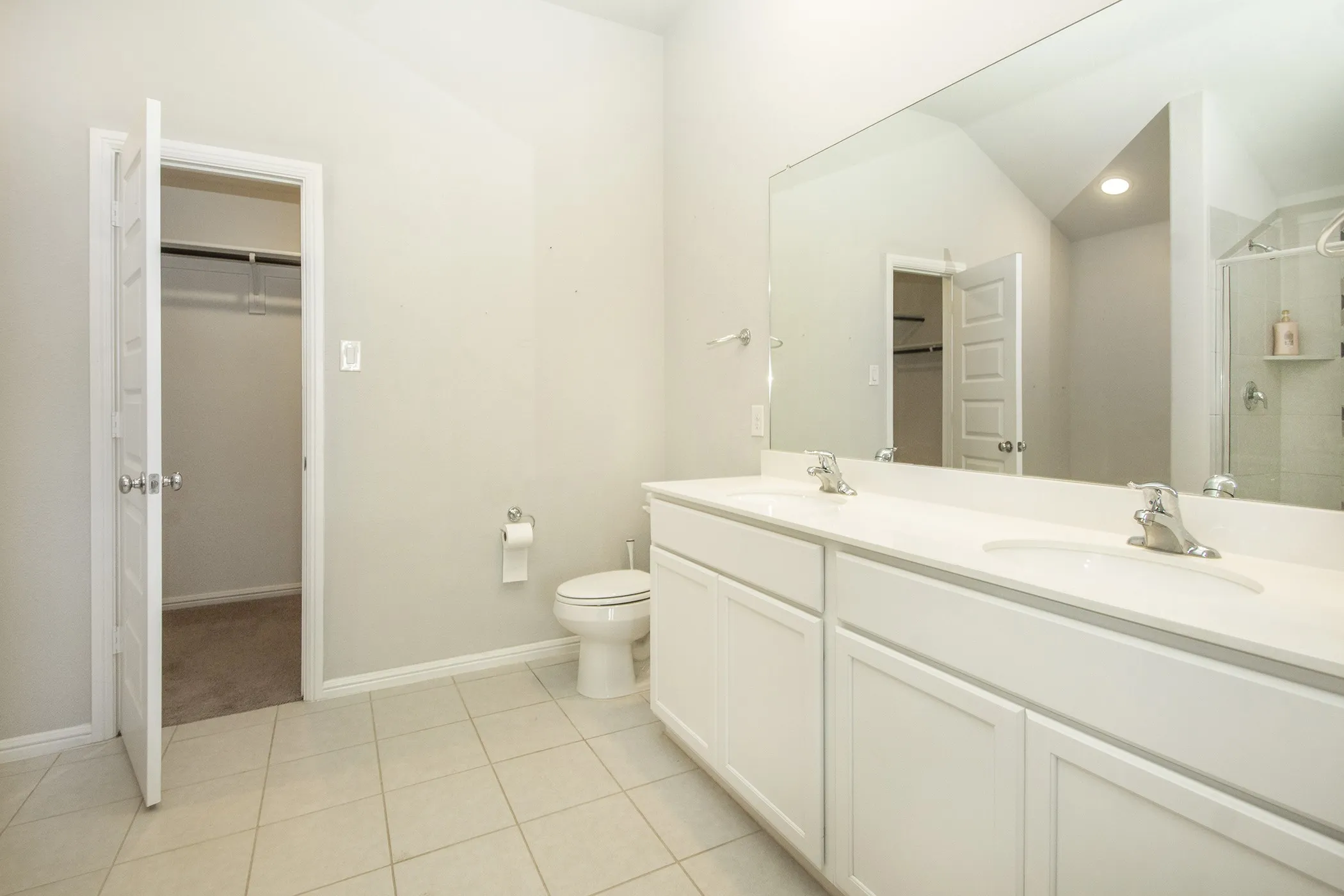 Full bathroom featuring a spacious closet, double vanity, tile patterned flooring, and an enclosed shower