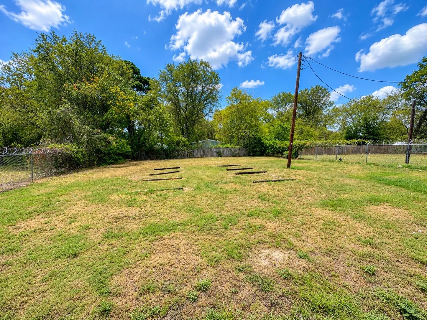 Expansive grassy area with mature trees and perimeter fencing