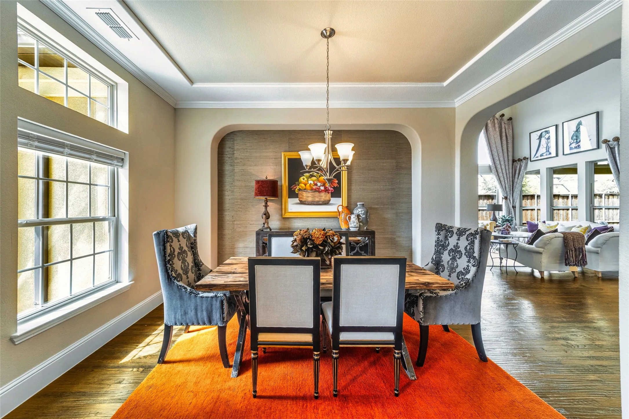 Hardwood flooring, arched doorways, crown molding, a tray ceiling, and a chandelier