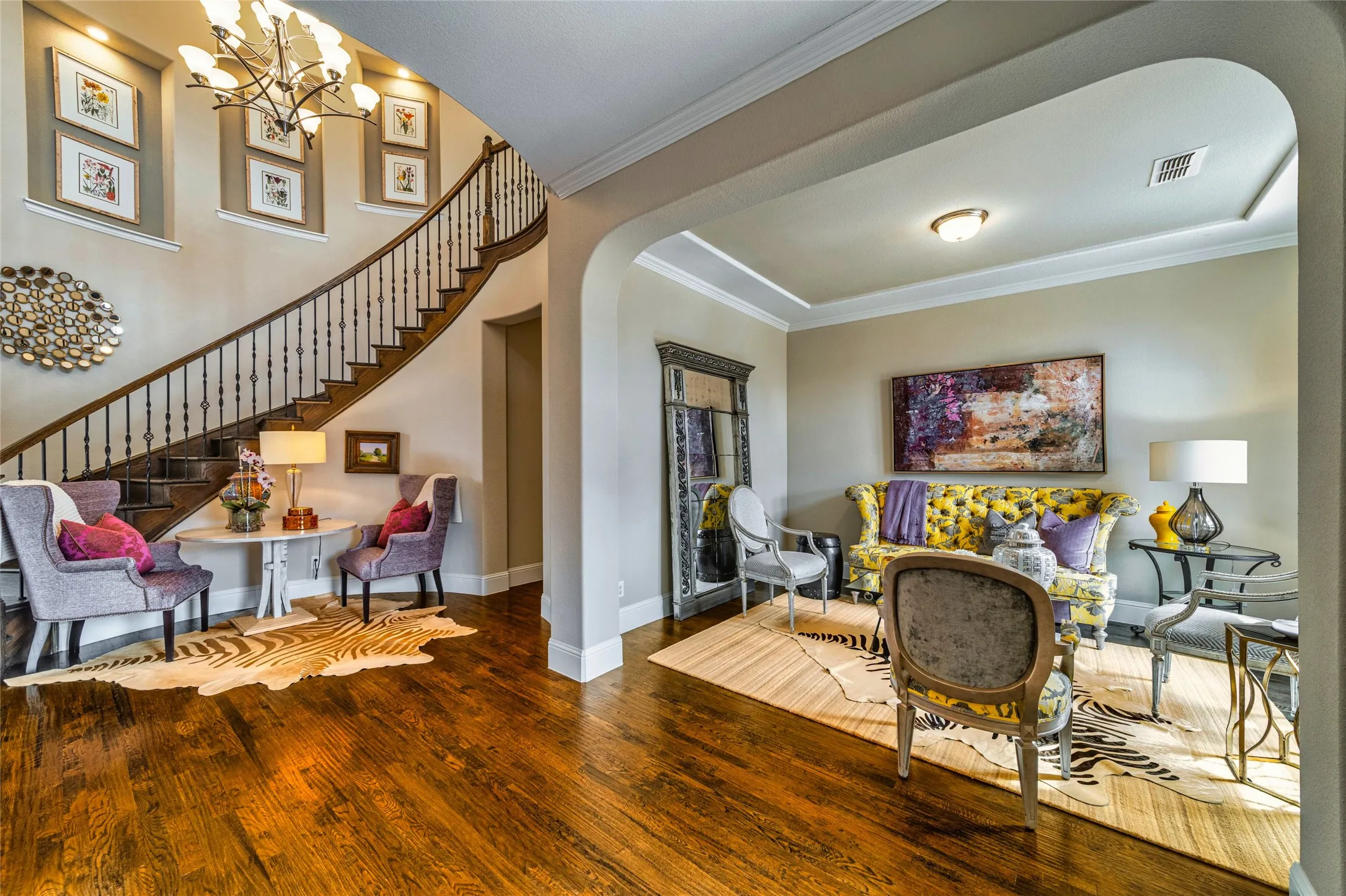 Hardwood flooring, curved staircase with wood banister, archway entry, crown molding, and recessed lighting