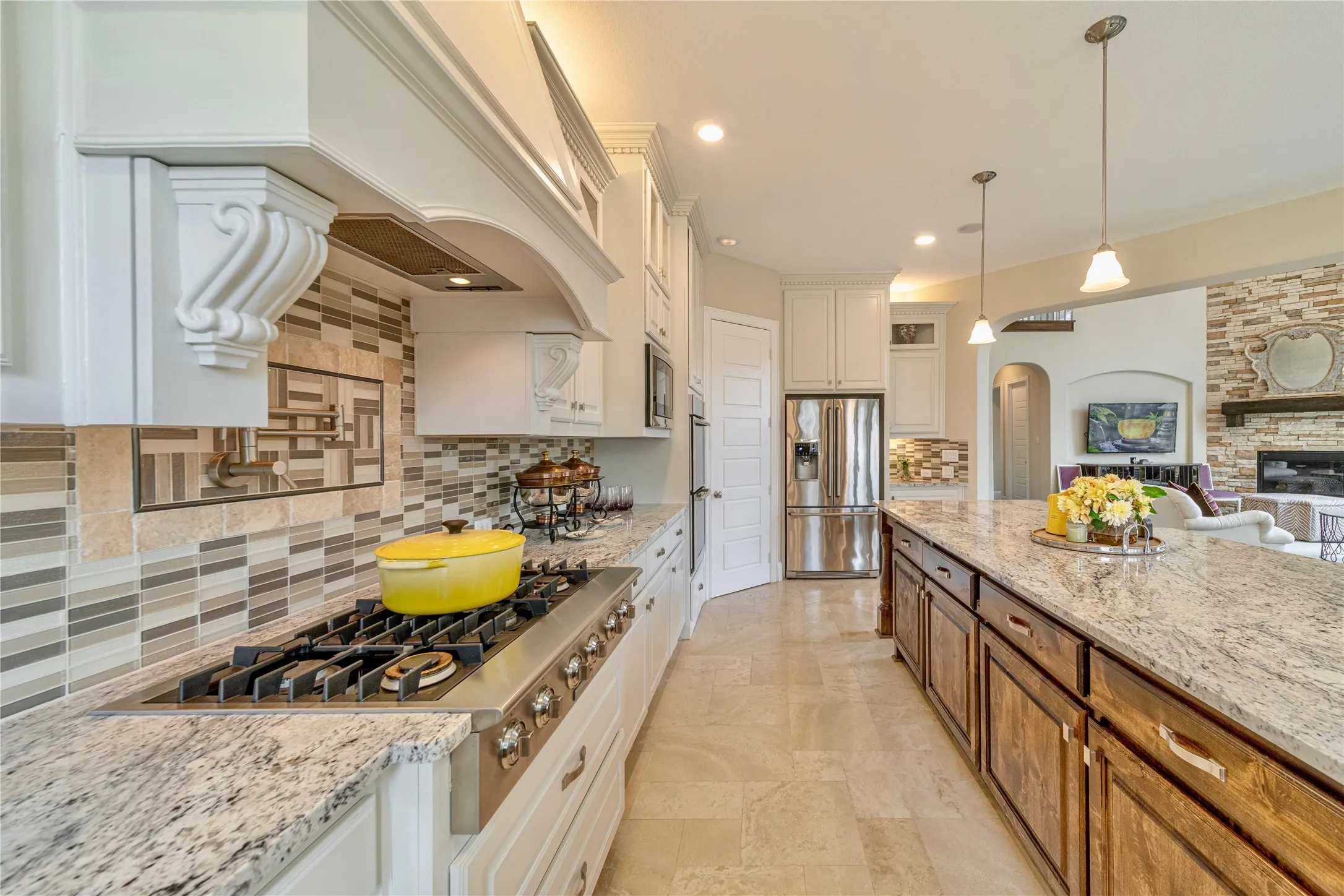 Gourmet kitchen featuring a built-in Electrolux gas range, white cabinetry, granite countertops, and a large level 6 granite entral island