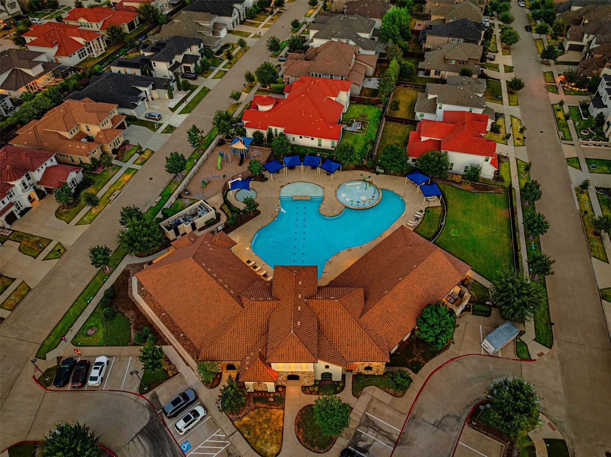 Community clubhouse with a multi-level pool, adjacent splash pad, and playground structure