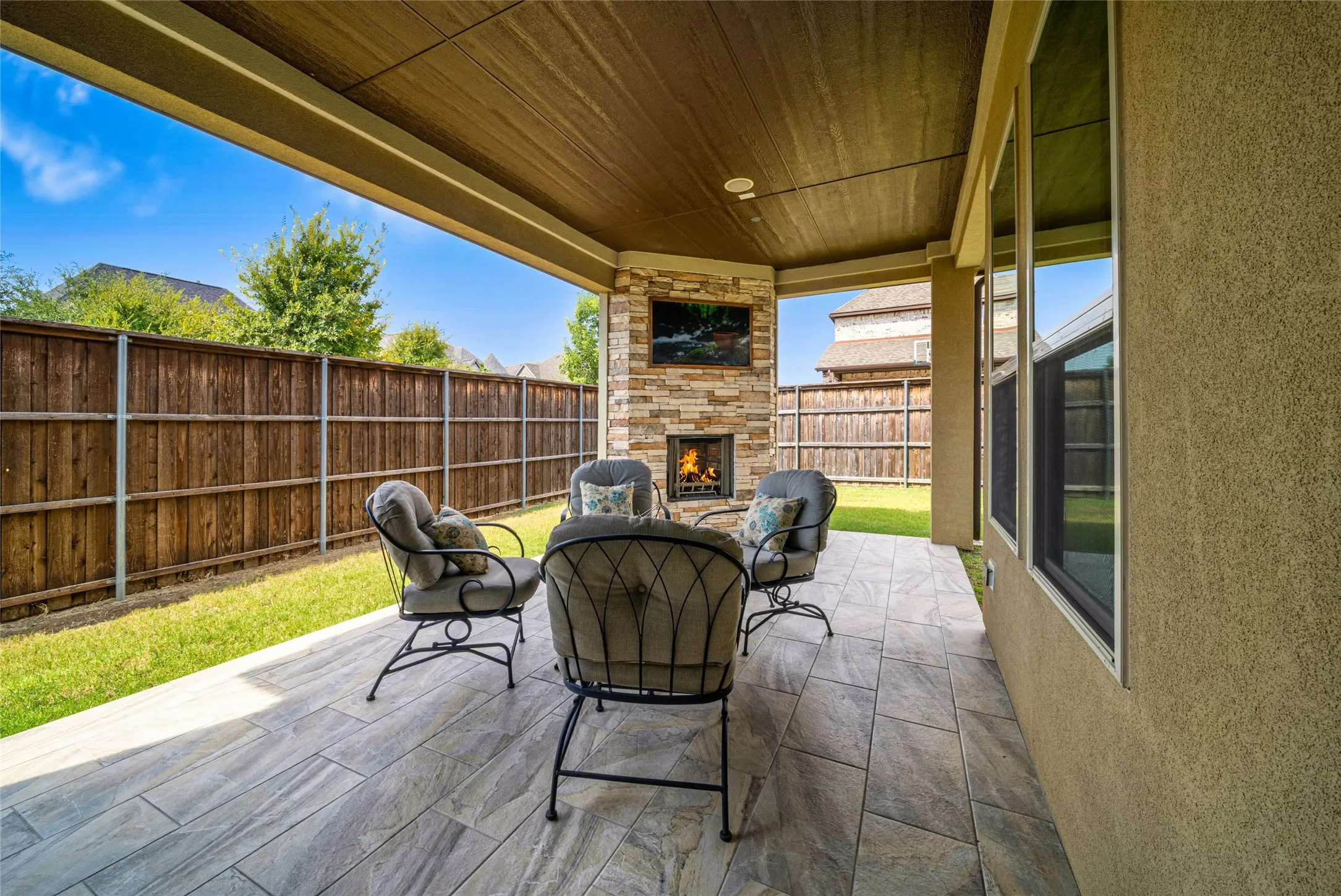 Covered patio with wood-finish ceiling, tiled flooring, and a stacked stone fireplace