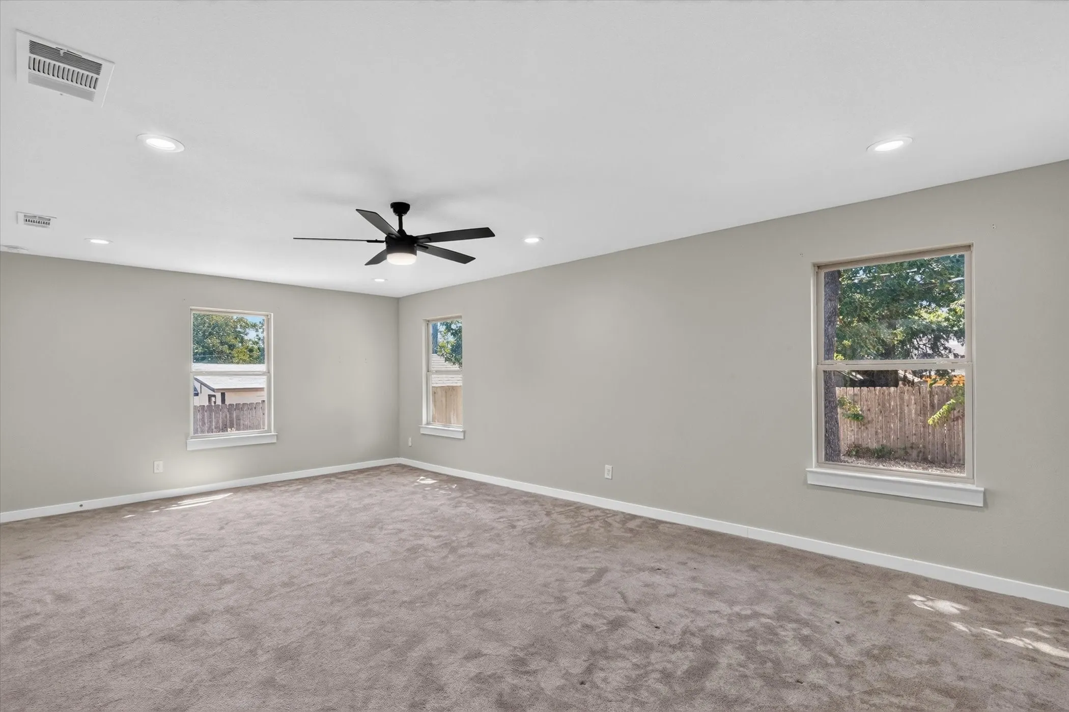 Recessed lighting, ceiling fan, neutral wall paint, and multiple windows