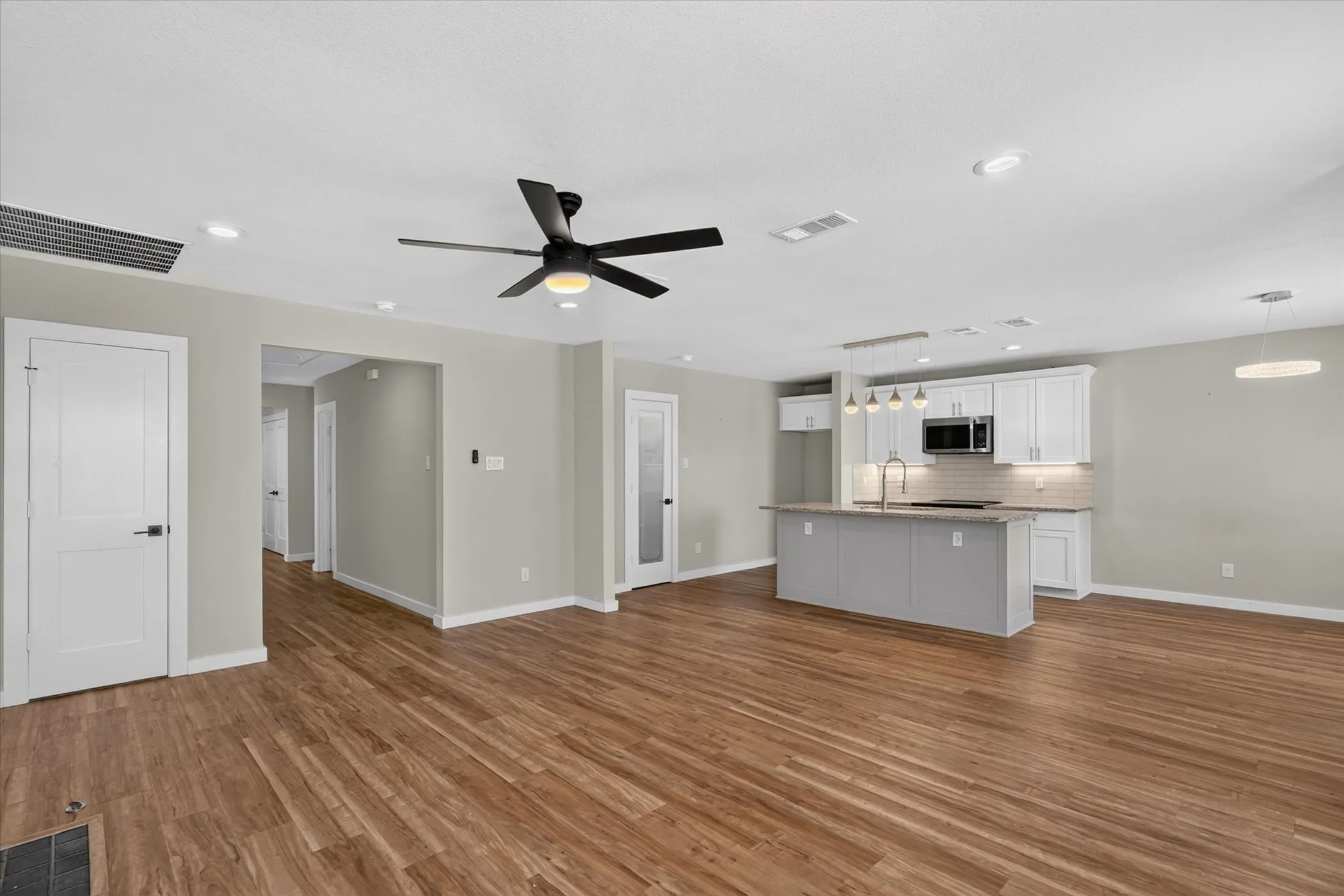 Open-concept living area featuring wood-finish flooring, recessed lighting, and a contemporary ceiling fan