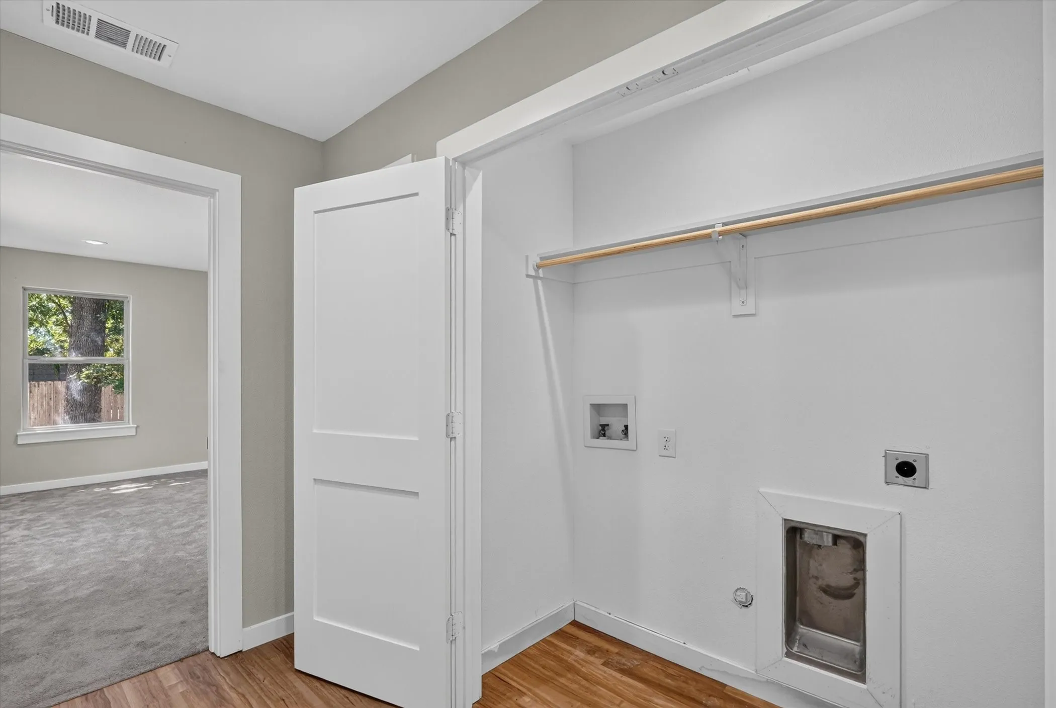 Dedicated utility area with wood-finish flooring, built-in shelving, and a clothing rod