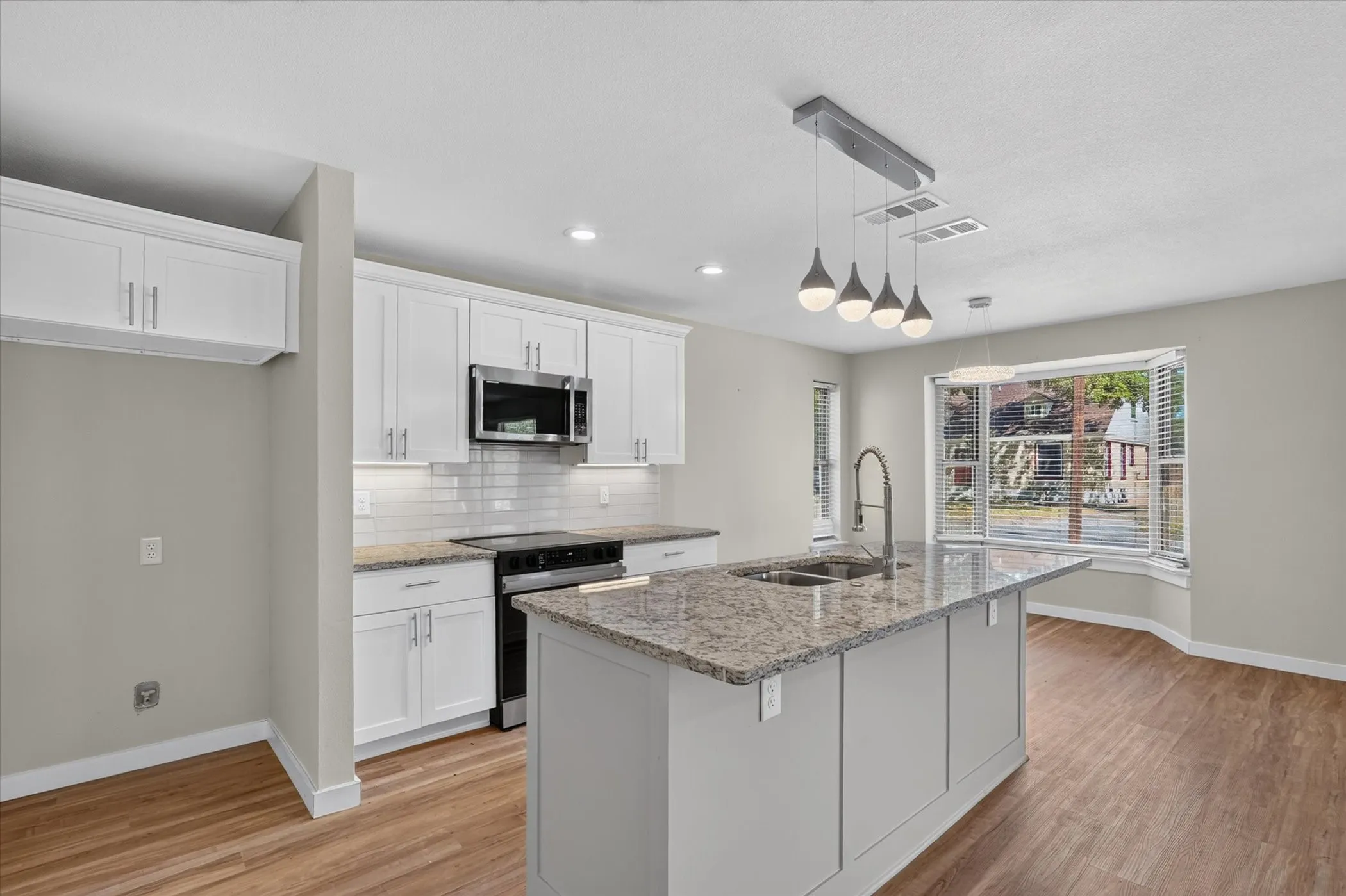 Kitchen featuring white shaker cabinetry, stainless steel appliances, granite countertops, and a subway tile backsplash