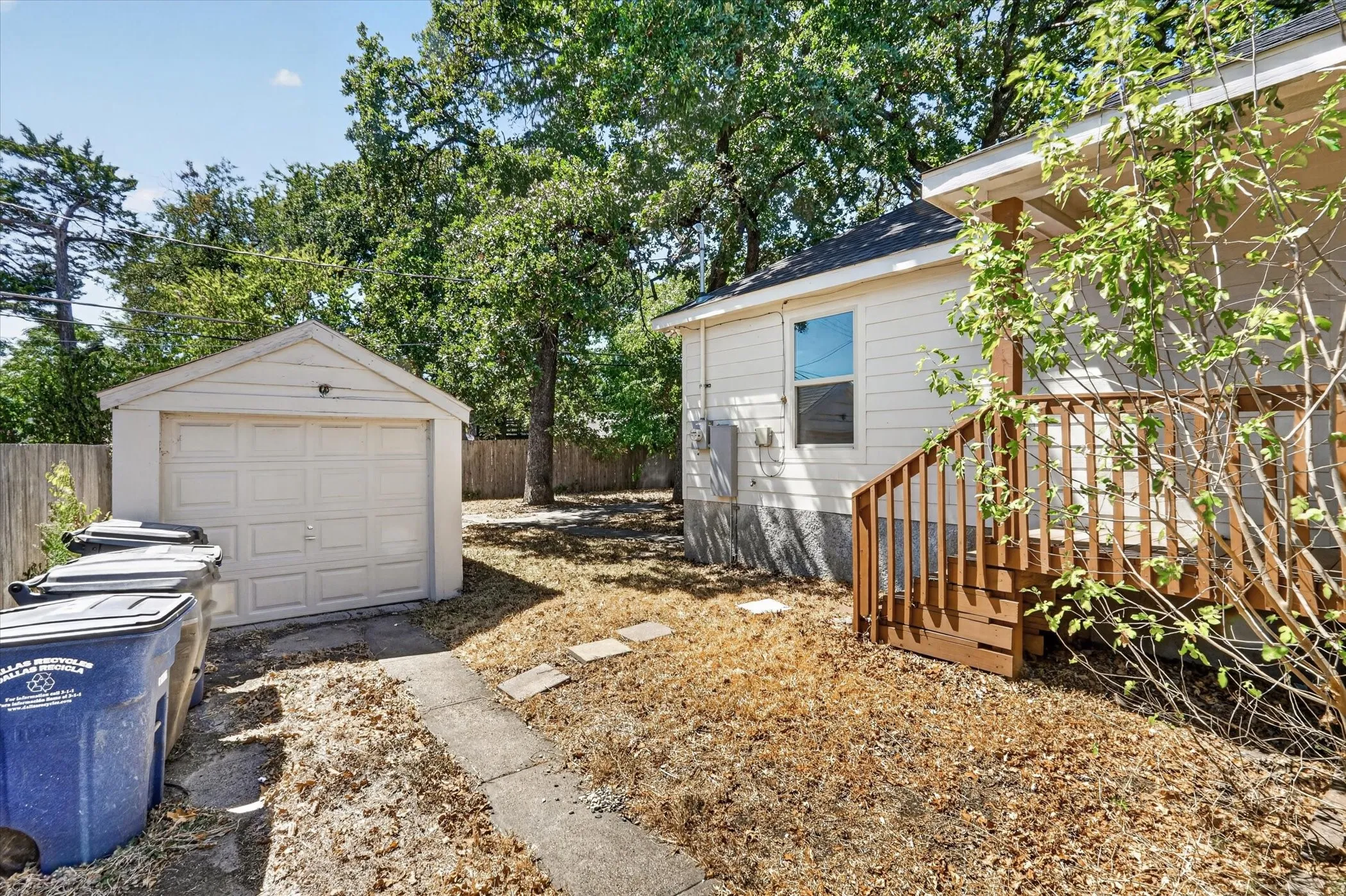 Detached garage with a paneled door, wood privacy fencing, and mature trees