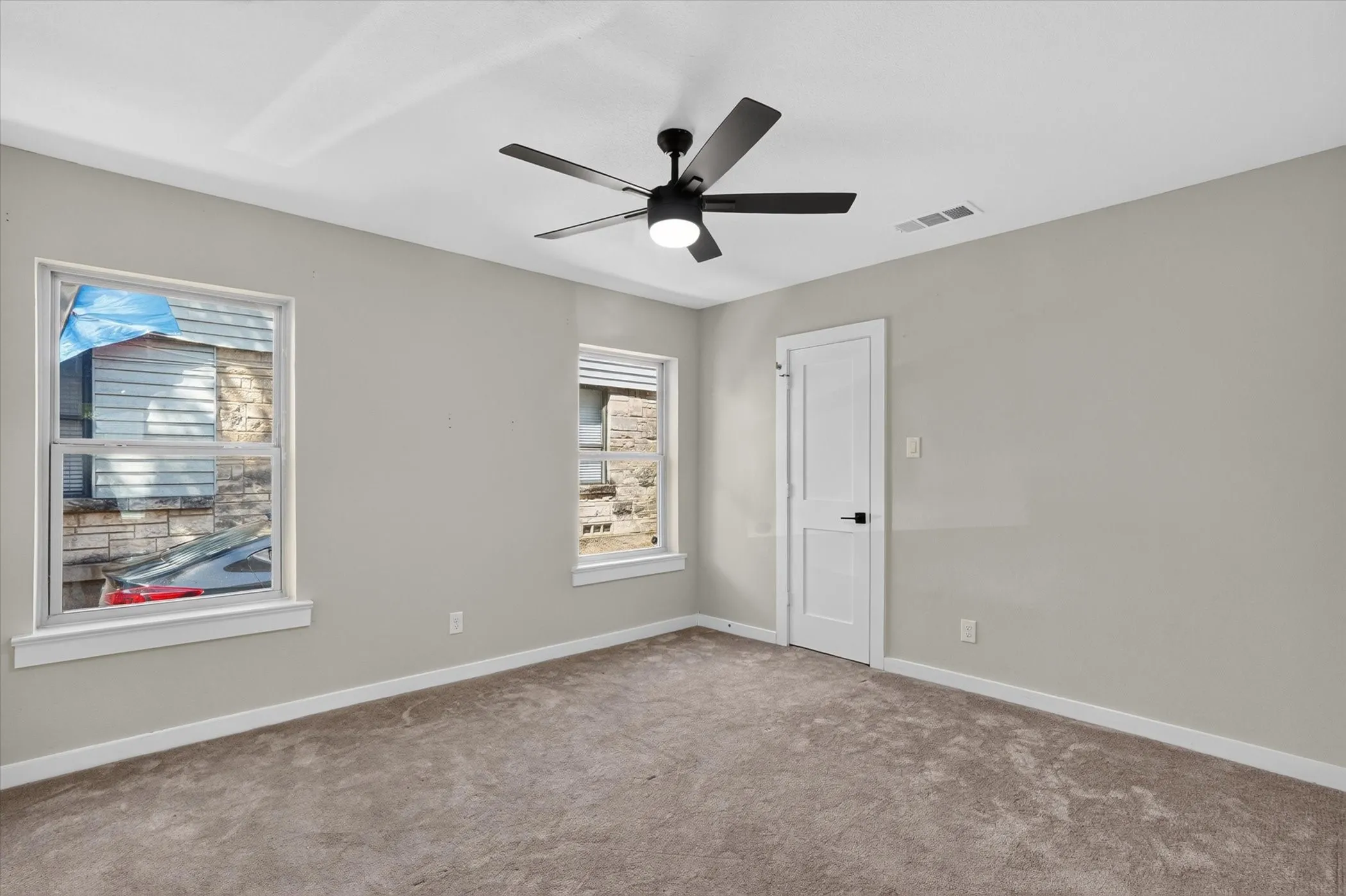 Neutral paint finishes, plush carpeting, a modern ceiling fan, and white trim work
