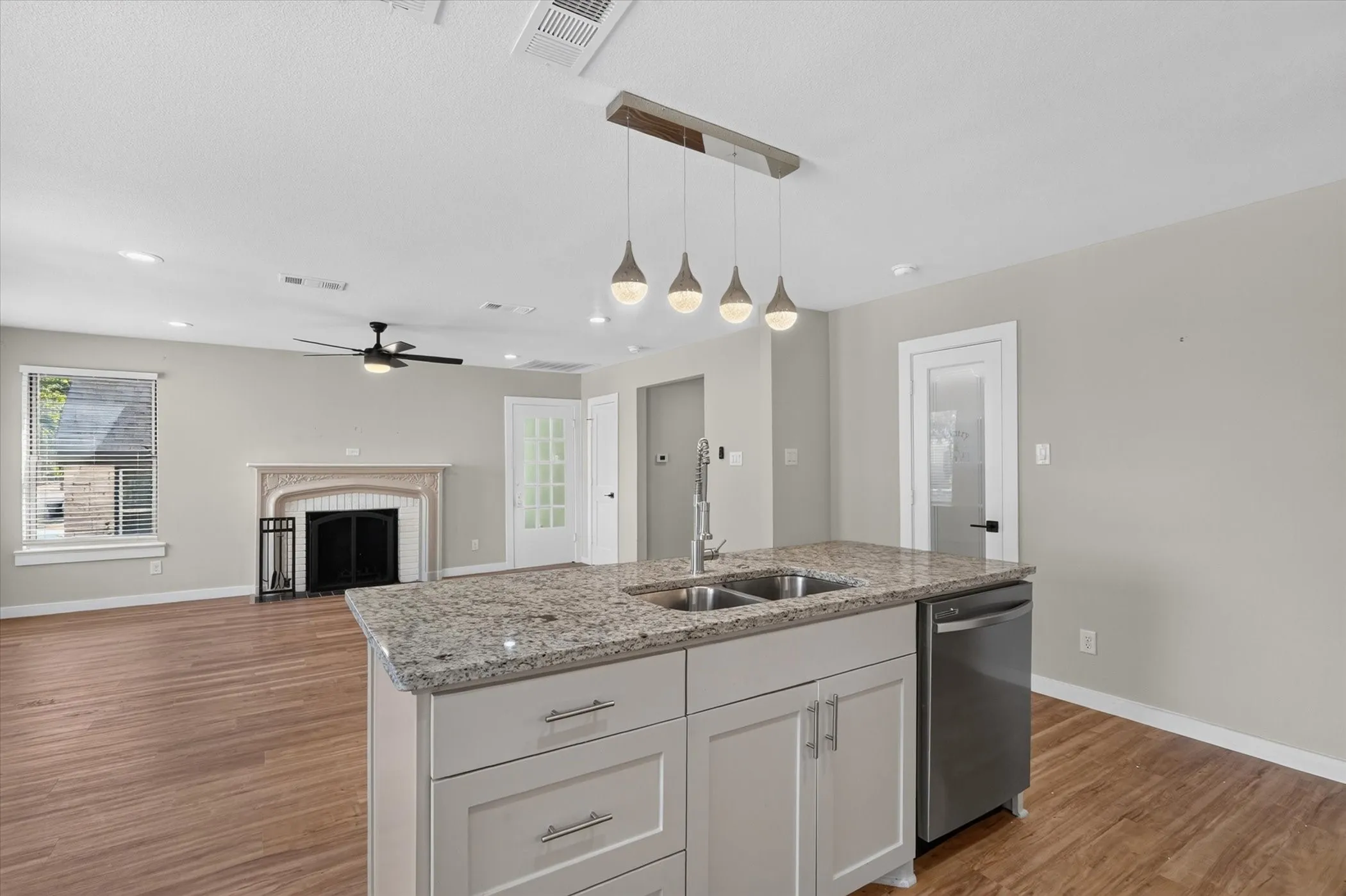 Kitchen island with granite countertop, double stainless steel sink, and pendant lighting