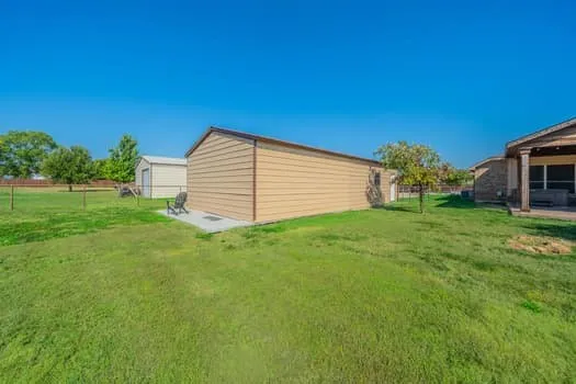 Expansive grass lawn with multiple outbuildings, including a large metal building that has various use