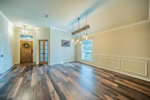 Vaulted ceilings, plank wood-finish flooring, decorative wainscoting, and a rustic wood beam chandelier