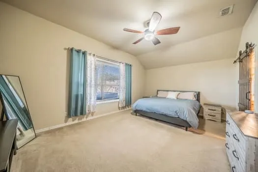 Vaulted ceiling, ceiling fan, window with blinds, carpeted flooring, barn door, nice size window seat
