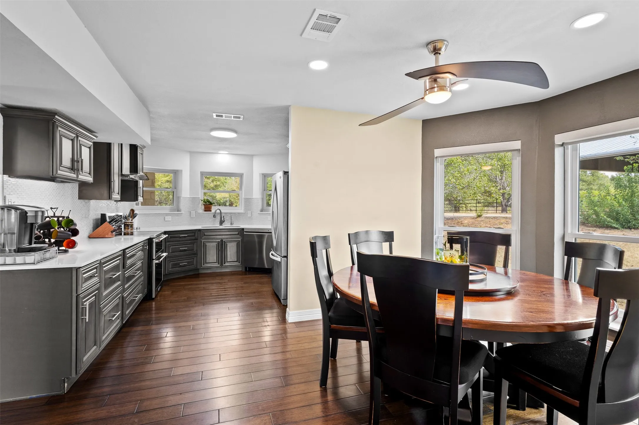 Kitchen featuring dark wood-finish flooring, grey cabinetry, white countertops, and a white subway tile backsplash