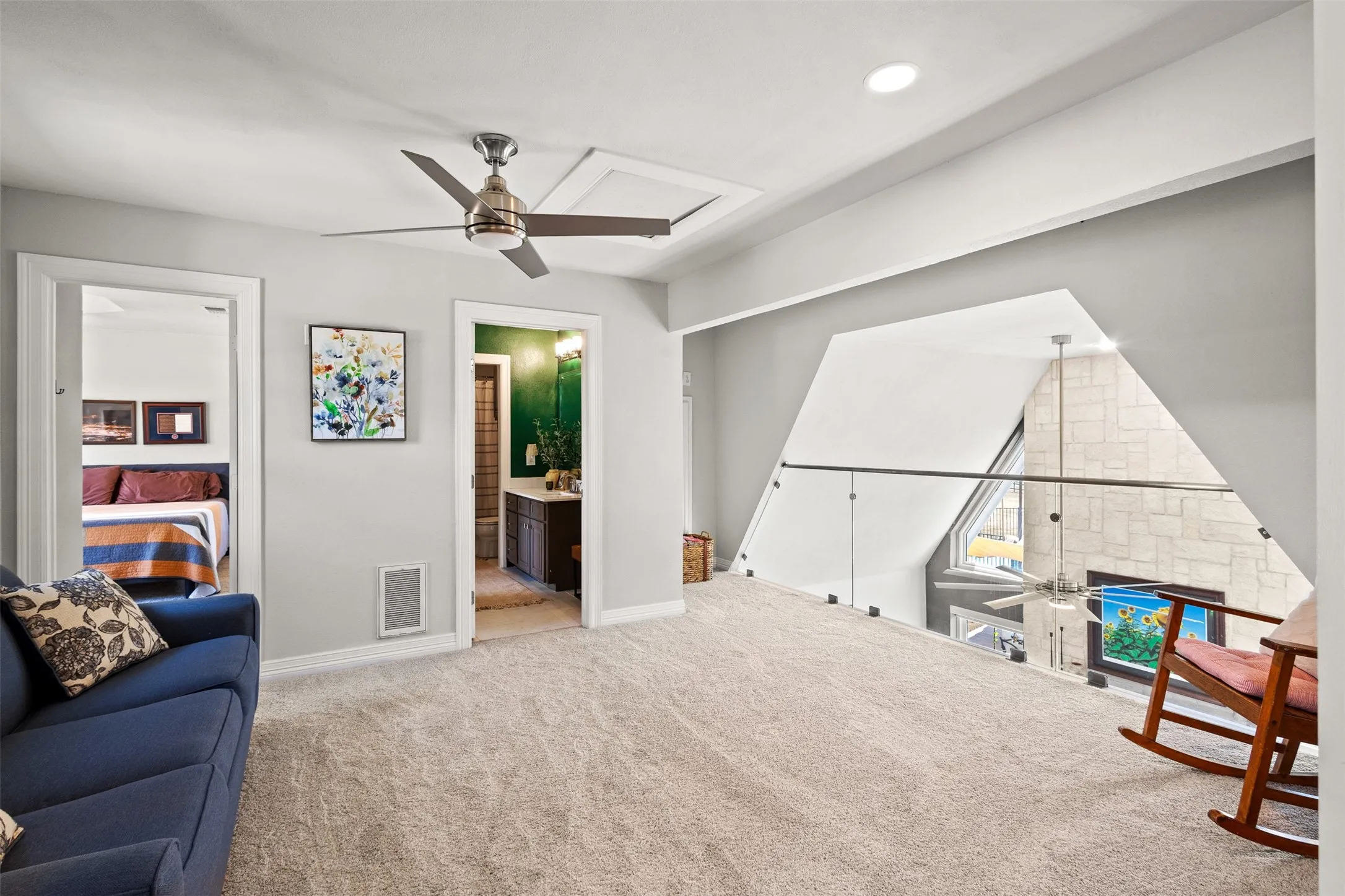 Upstairs loft area with a ceiling fan, recessed lighting, and a glass-paneled railing overlooking the lower level