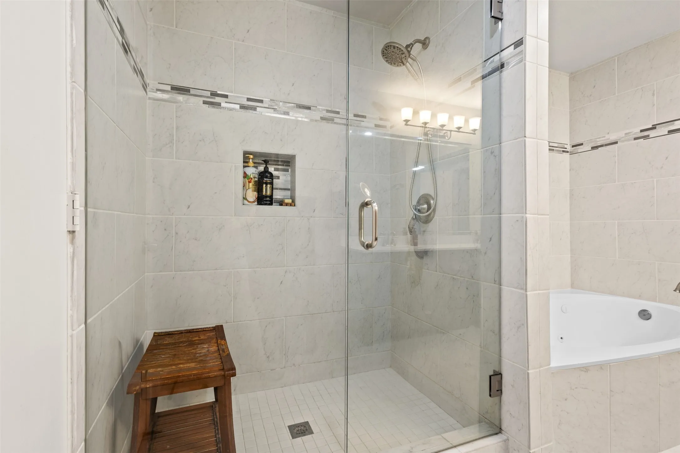 Enclosed shower with clear glass door, tile surround, recessed storage niche, and integrated showerhead