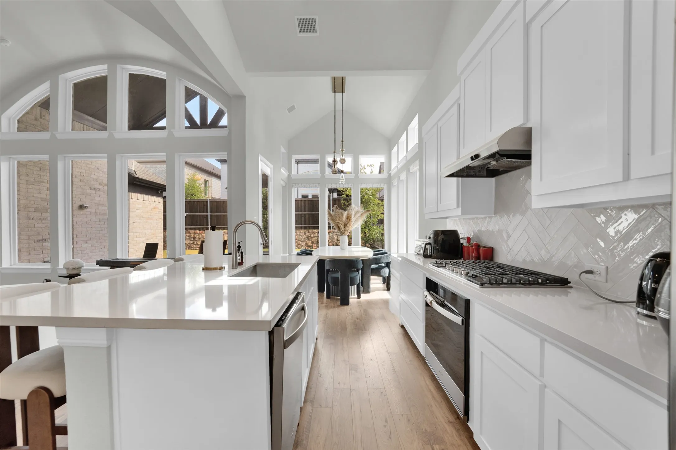 Kitchen featuring white cabinetry, light countertops, a stainless steel gas range, and a herringbone tile backsplash
