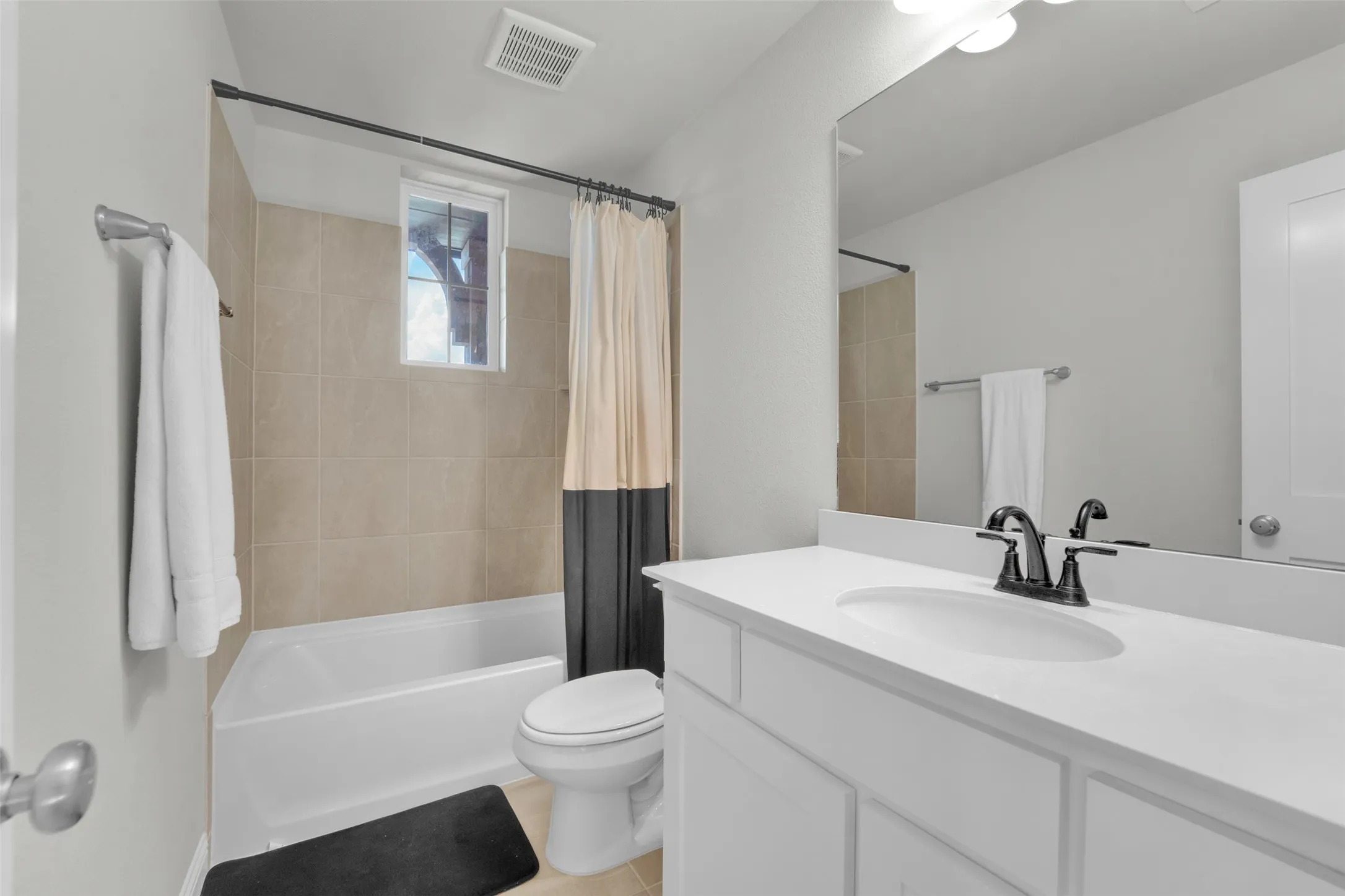 White vanity with integrated sink, black dual-handle faucet, and large wall-mounted mirror