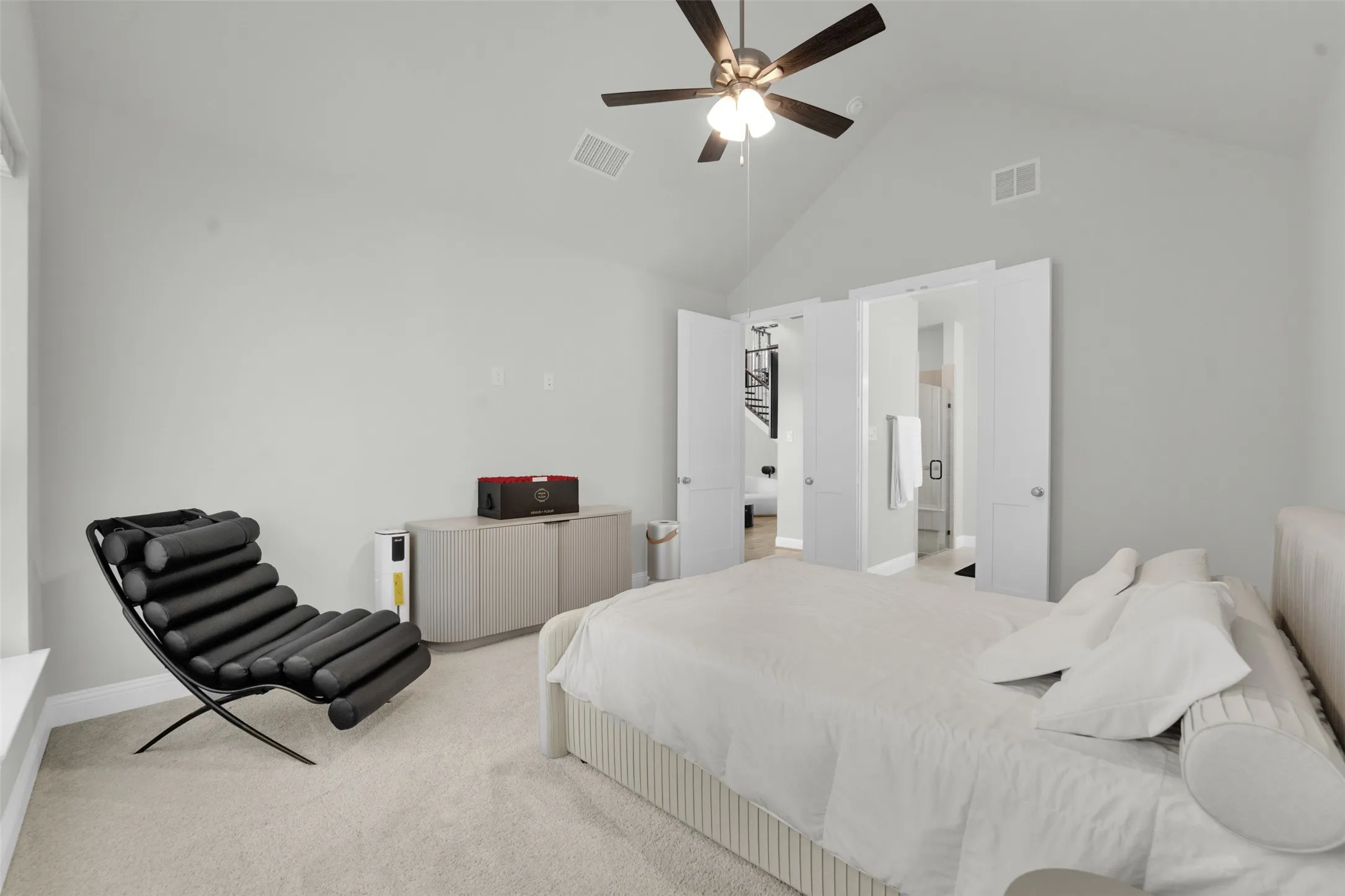 Vaulted ceiling, ceiling fan, white paneled doors, light neutral wall color, and light-colored carpeting
