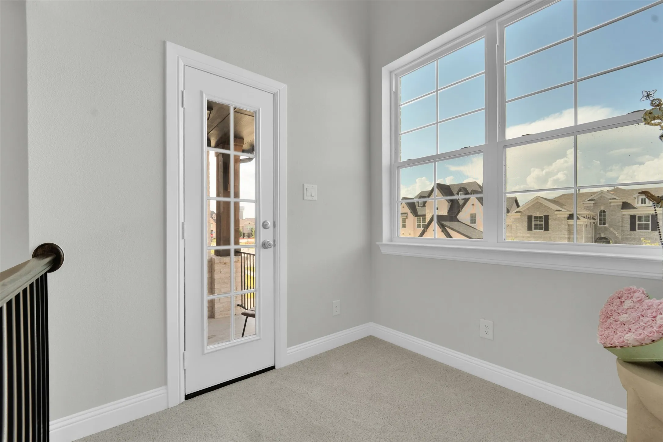 Light gray wall paint, white trim, light-colored carpeting, French door with glass panels, and large multiple-pane windows