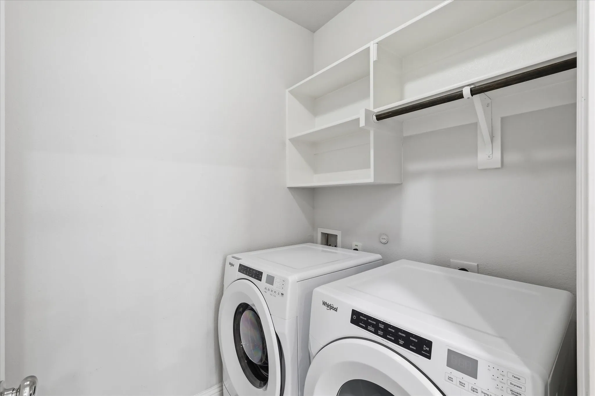 Laundry area with a white shelving system and a hanging rod