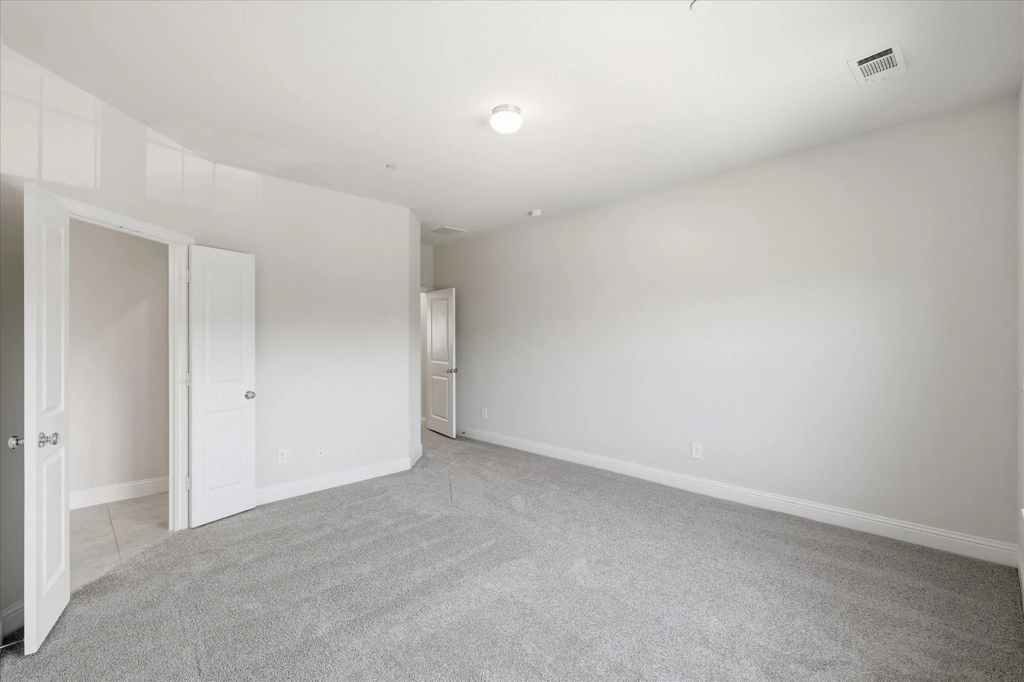 Spacious room with light gray carpeting, neutral wall finishes, and recessed lighting