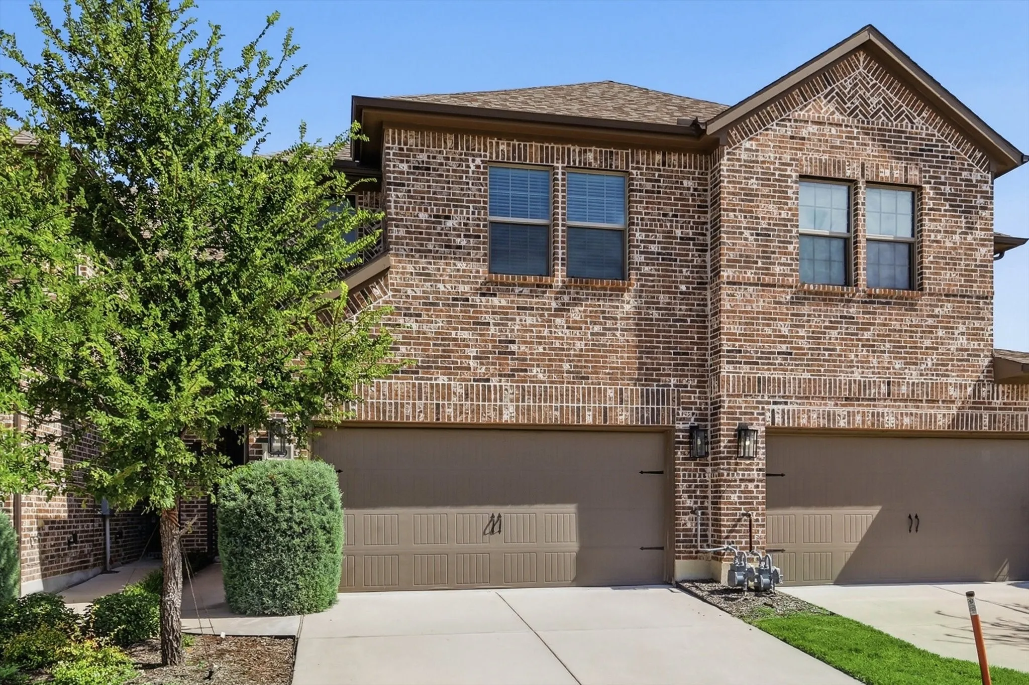 Brick exterior with brown garage doors and asphalt shingle roof