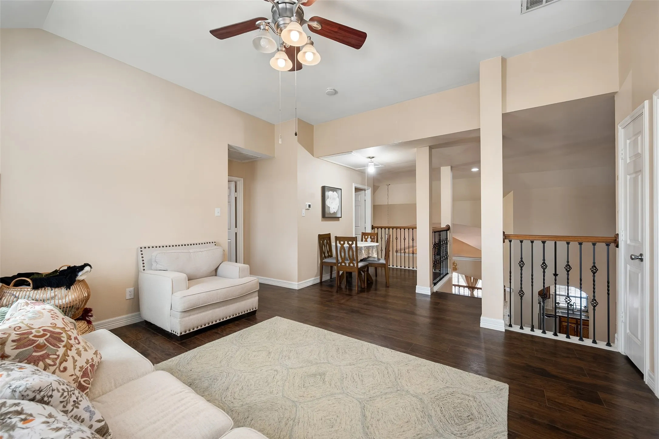 Third living area upstairs- featuring hardwood flooring, a ceiling fan with integrated lighting, a comfortable seating area with an upholstered chair, and direct access to a gated safety barrier