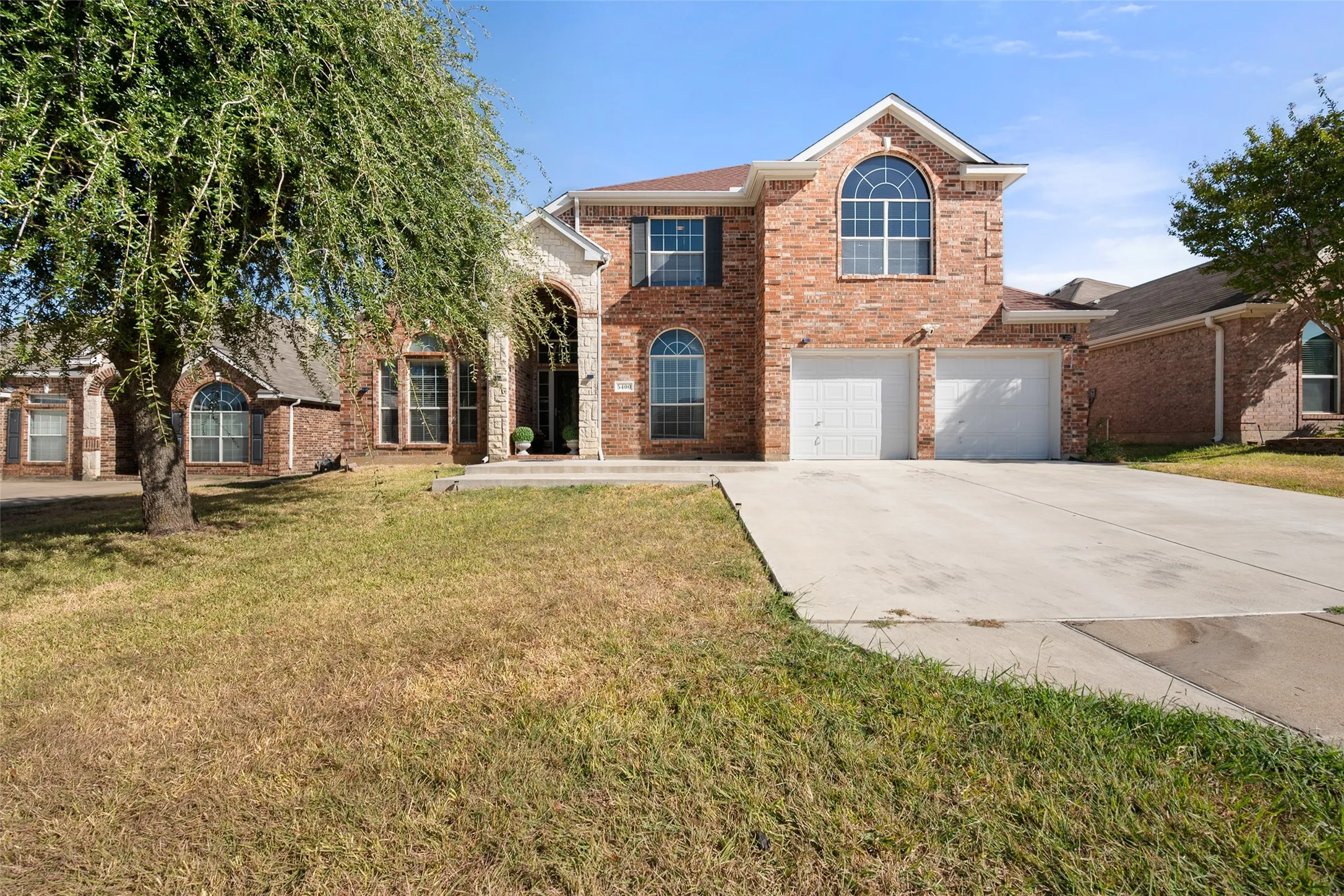 Brick facade with stone accents, arched entry, two-car garage, and multiple arched windows