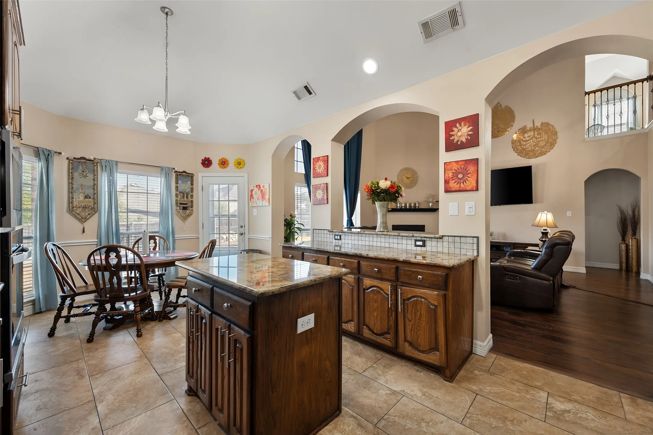 Kitchen island with stone countertop, tile flooring, arched doorways, and a built-in oven