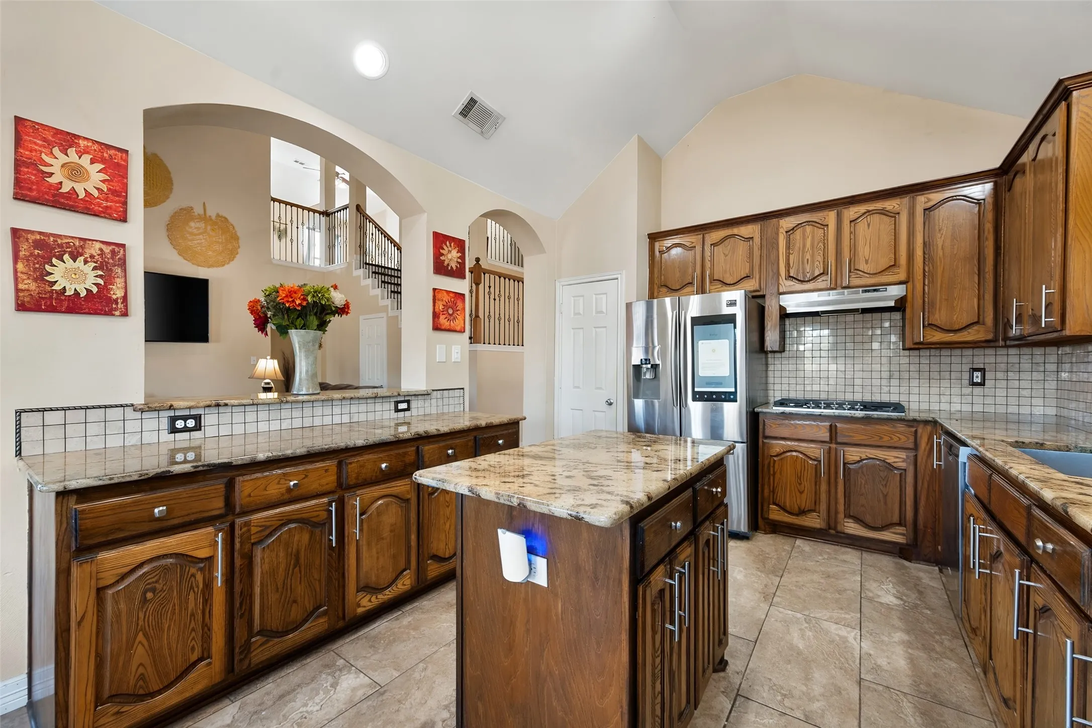 Kitchen featuring wood cabinetry, granite countertops, tile flooring, a tile backsplash, and stainless steel appliances