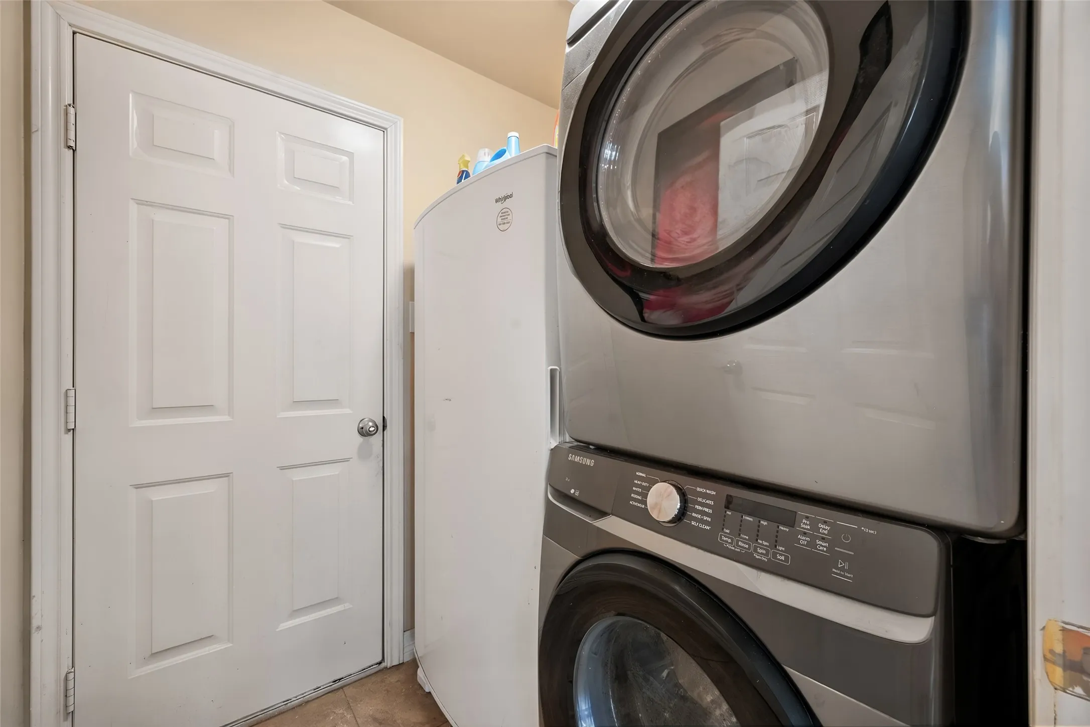 Laundry area with a stacked washer and dryer, adjacent to a paneled door and is located downstairs