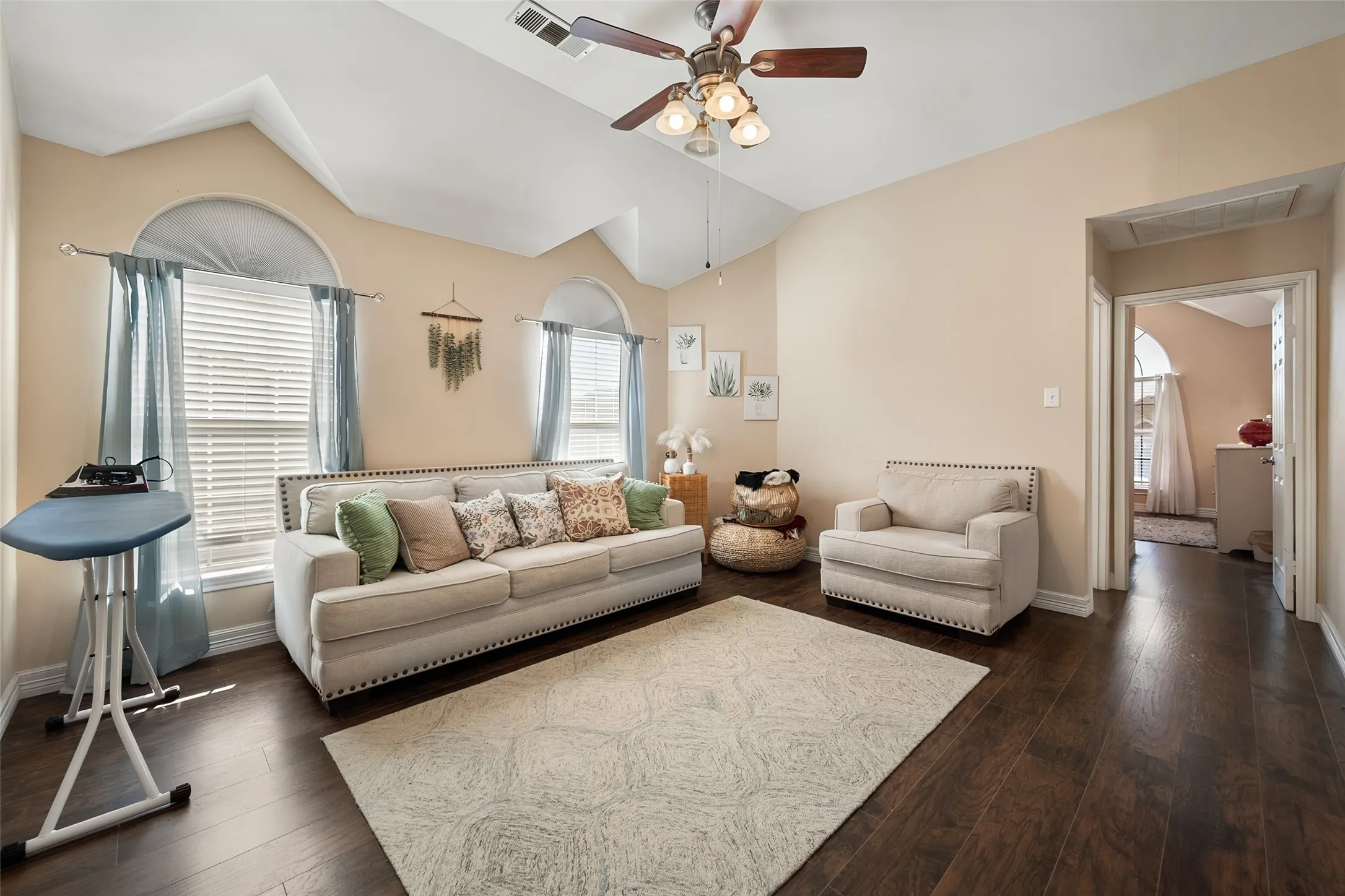 3rd living area ,Vaulted ceiling, wood-finish flooring, arched windows, ceiling fan, and neutral wall tones