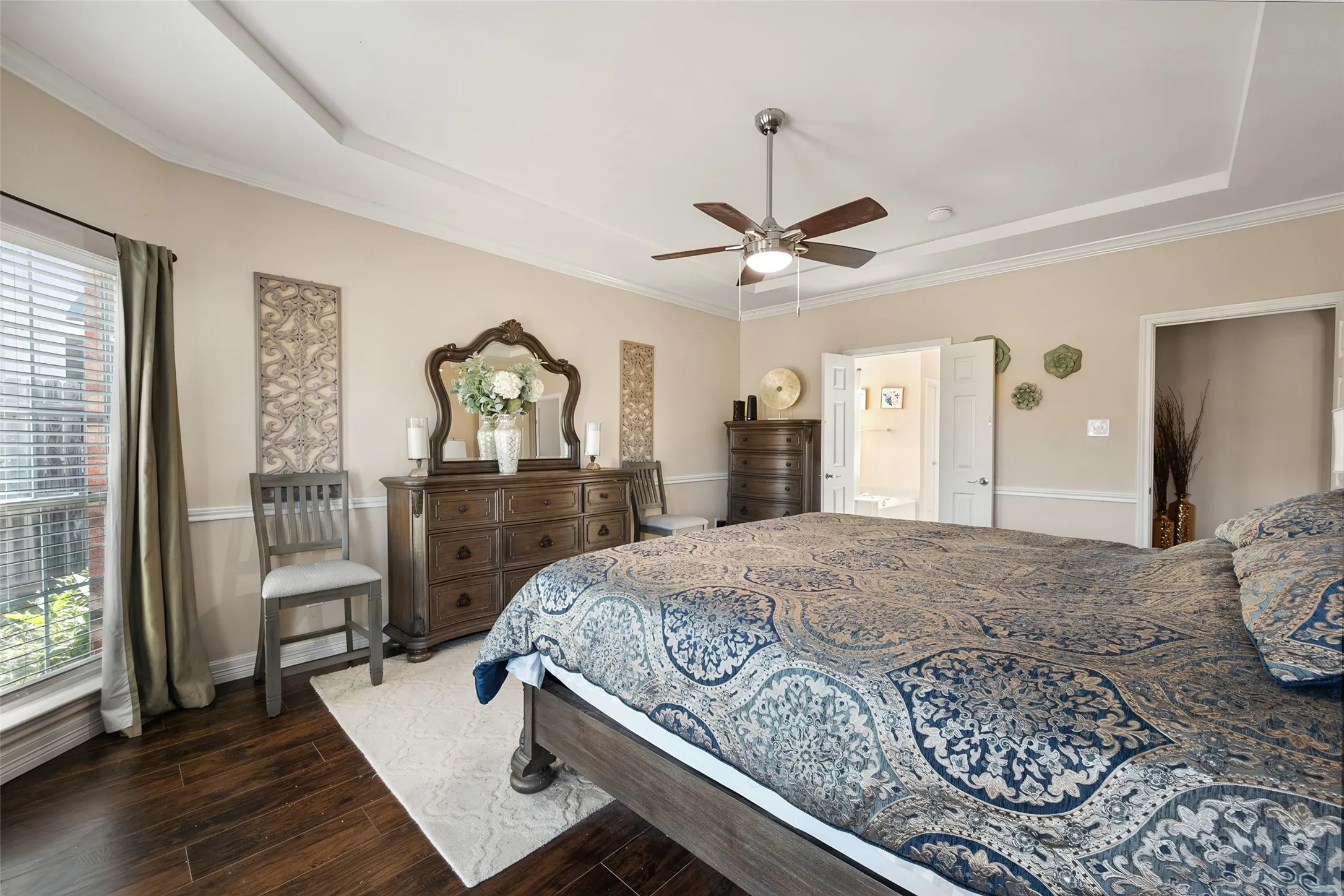 master bedroom,Tray ceiling with crown molding, ceiling fan, wood-finish flooring, and double-door entry