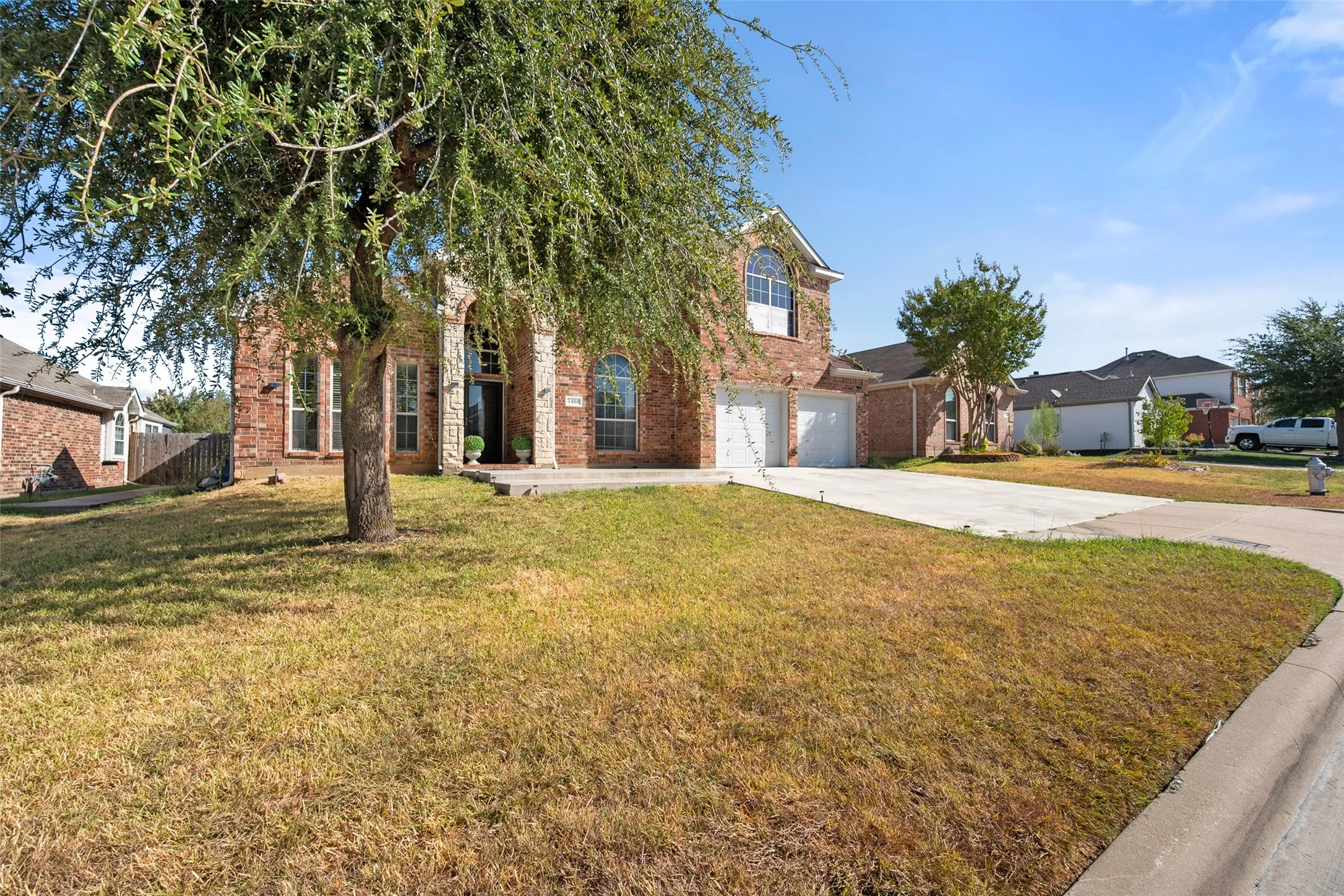 Brick exterior with stone accents, arched windows, a two-car garage, and a concrete driveway