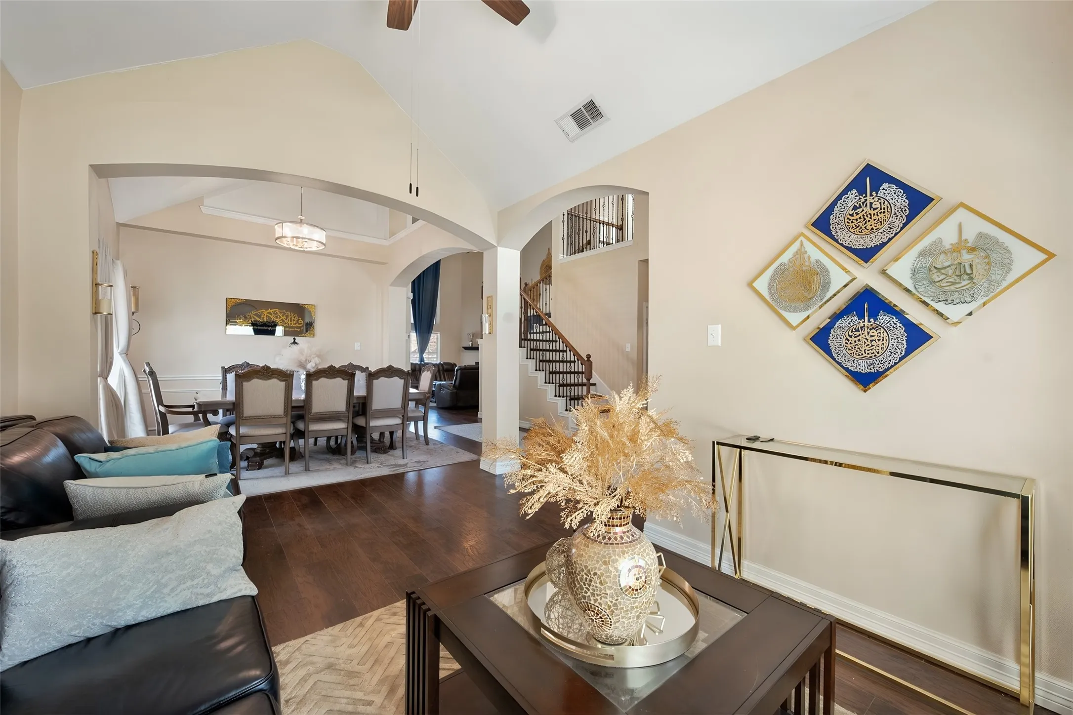 Wood-finish flooring throughout, arched doorways, a vaulted ceiling, and a prominent staircase with dark wood treads and white risers