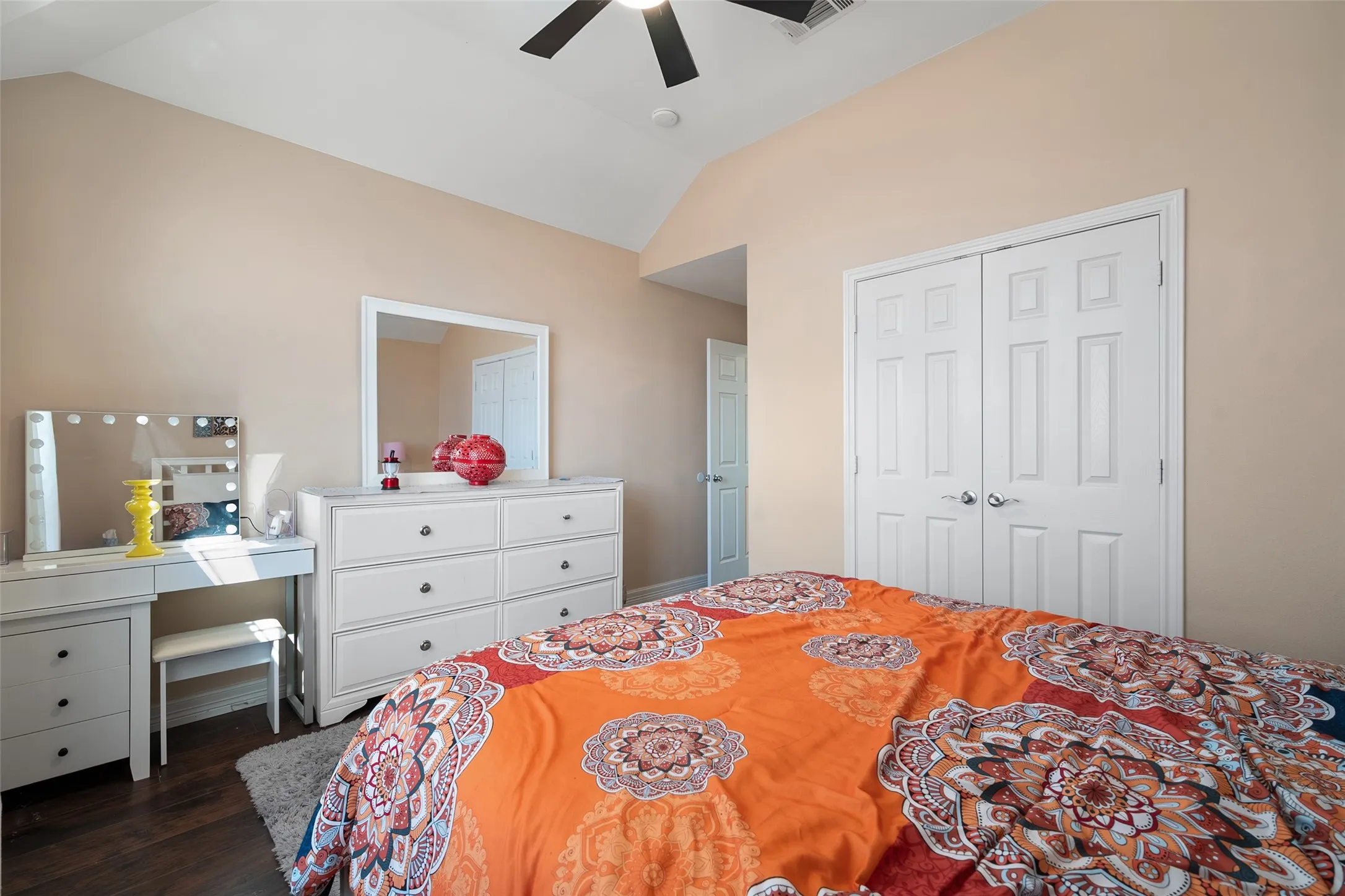 upstairs bedroom,Vaulted ceiling, ceiling fan, wood-finish flooring, light-toned wall paint, white bi-fold closet doors
