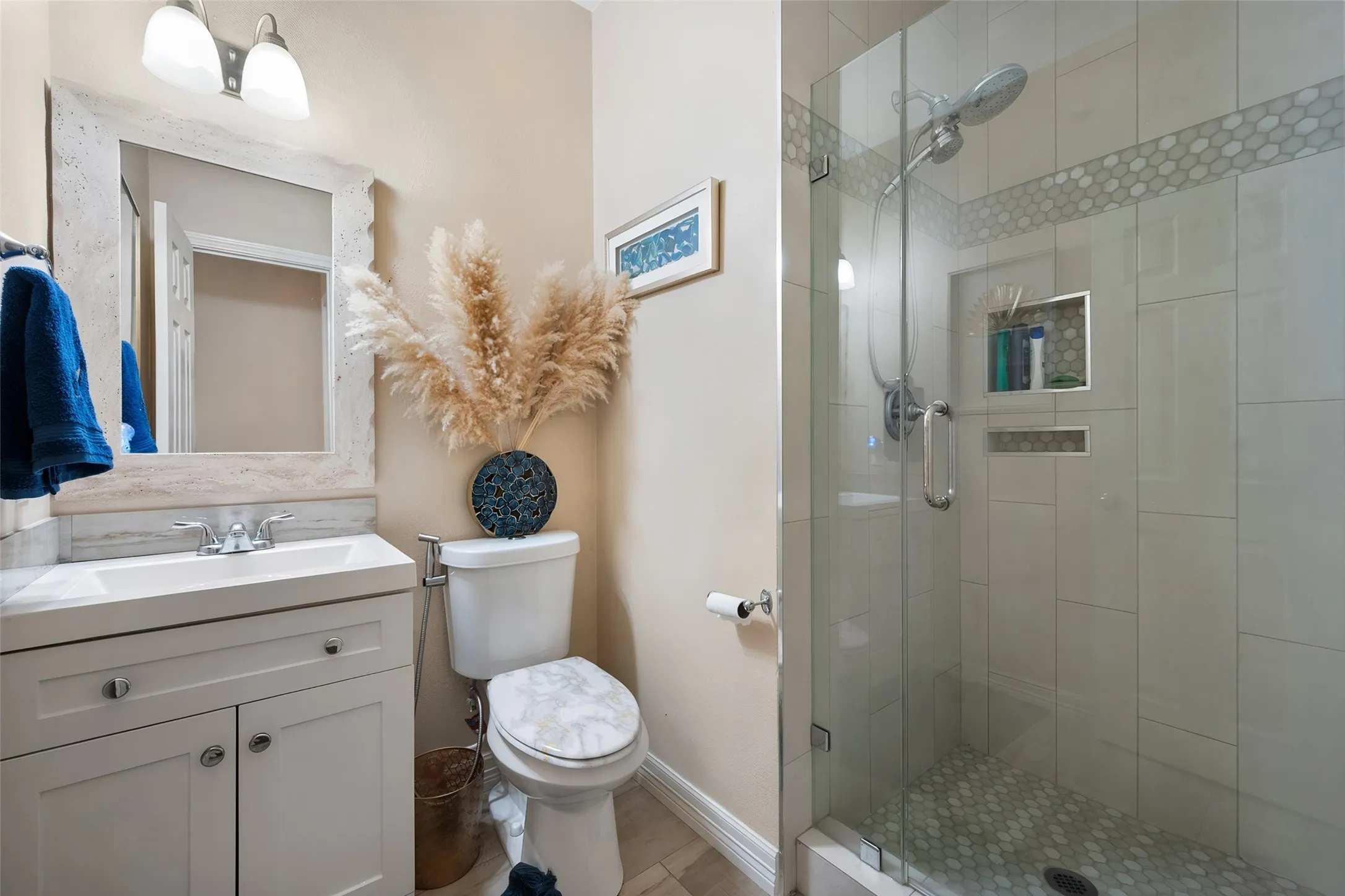 Glass-enclosed shower with a tiled surround, recessed shelf, and hexagonal tile flooring