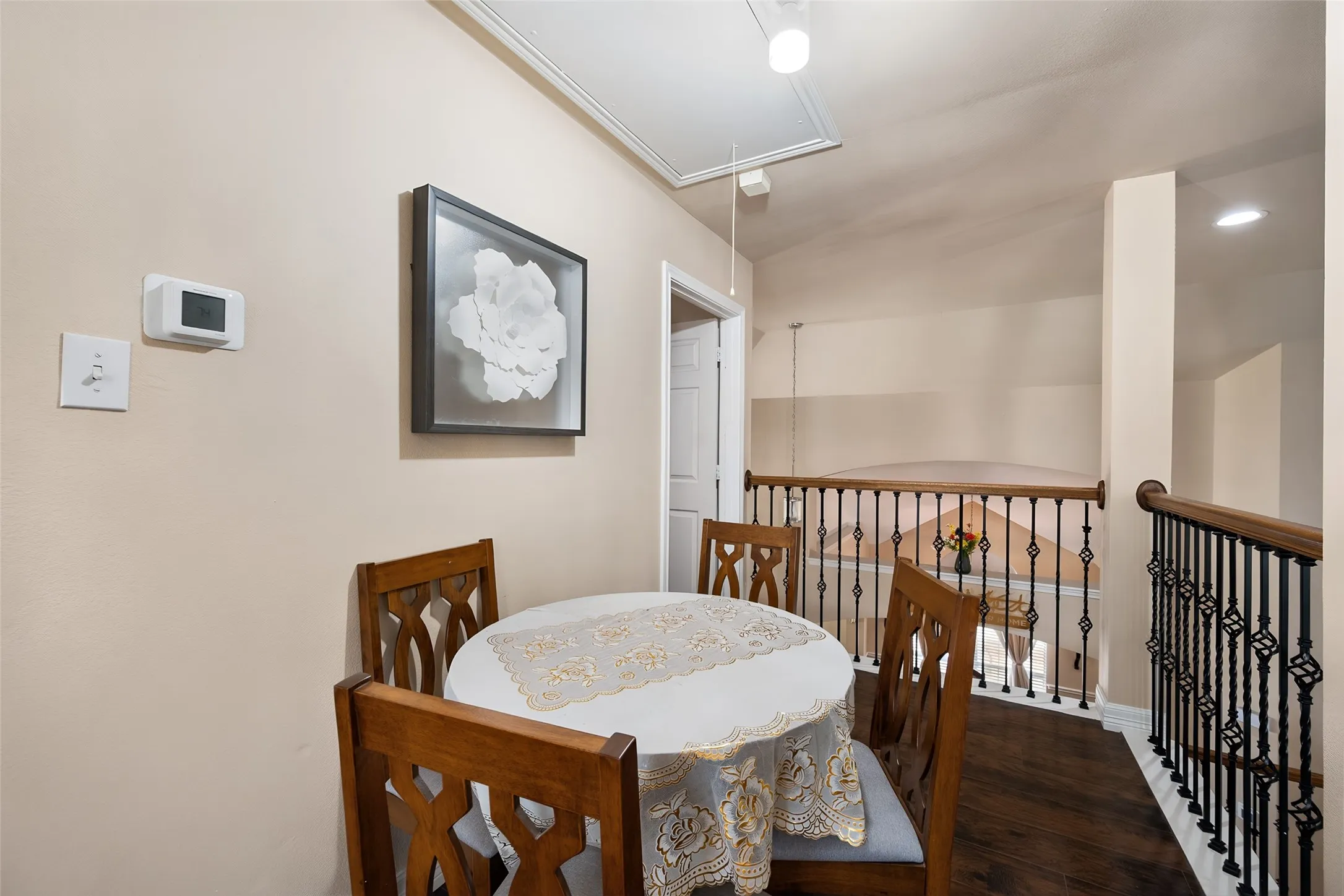 Wood-finish flooring with wrought iron railing and wood-capped banister